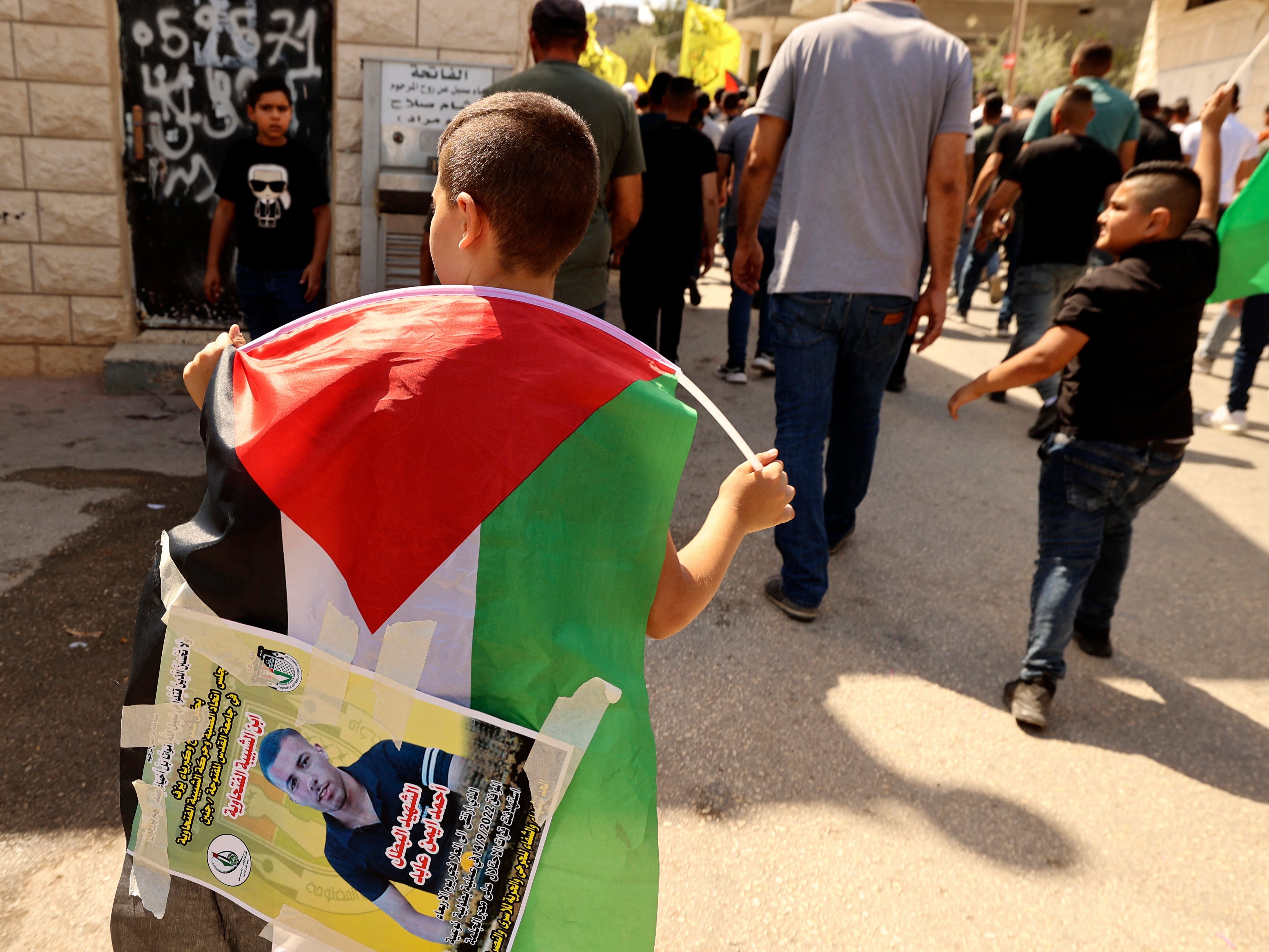 Seorang anak laki-laki membawa bendera nasional saat warga Palestina berbaris di desa Kafr Dan.