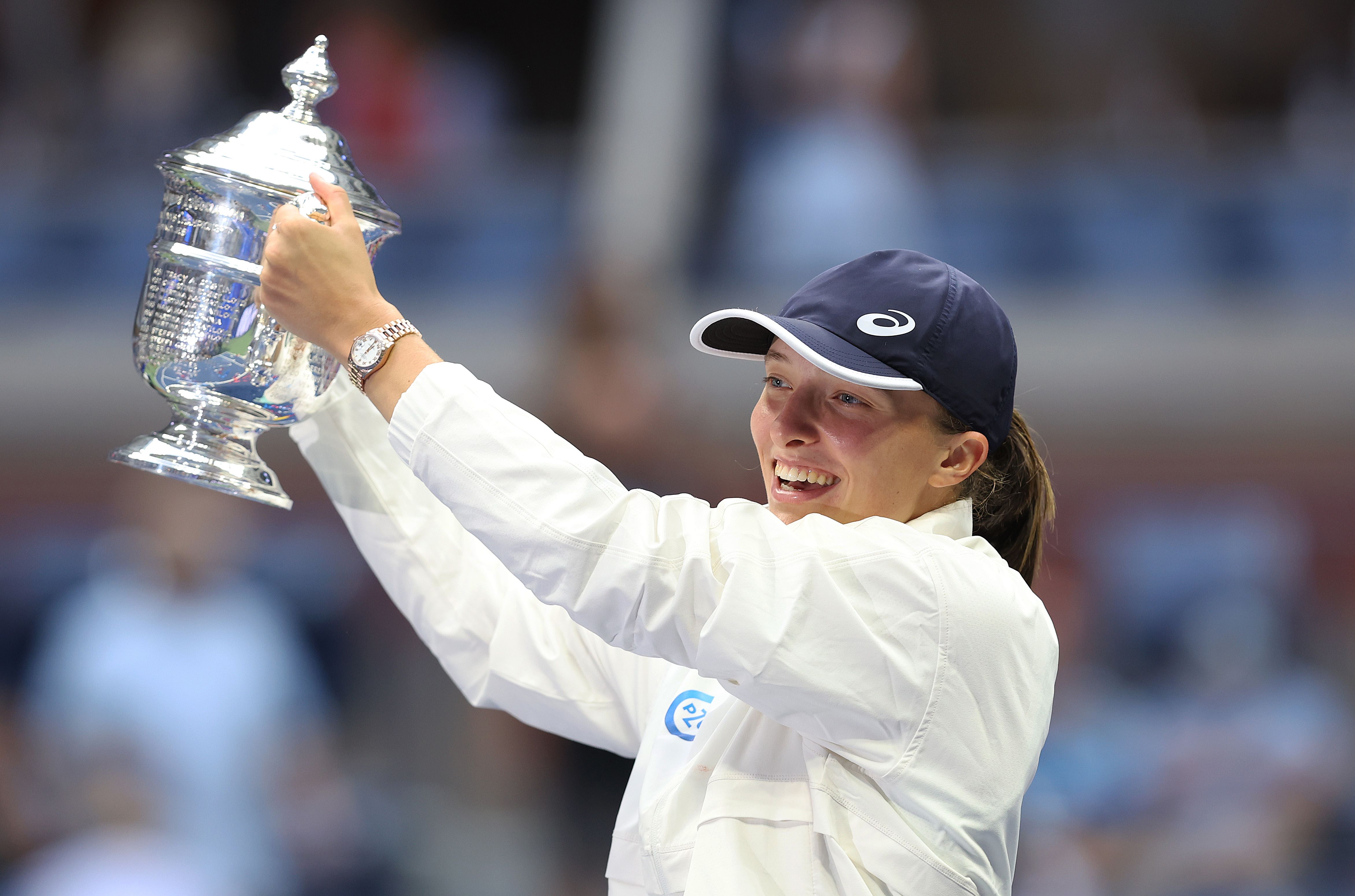 Petenis asal Polandia Iga Swiatek mengangkat trofi US Open yang diraihnya, Sabtu (10/9).