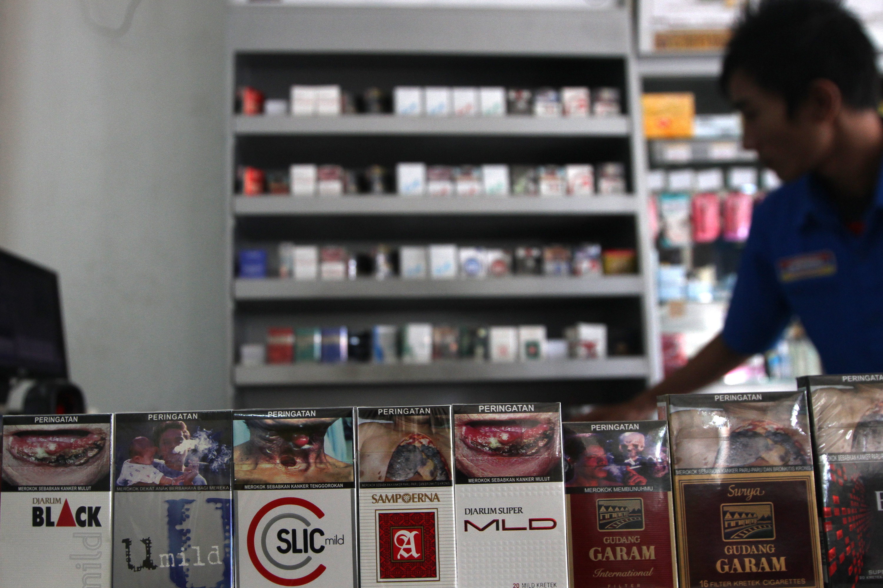 Pedagang menata bungkus rokok yang bergambar seram.