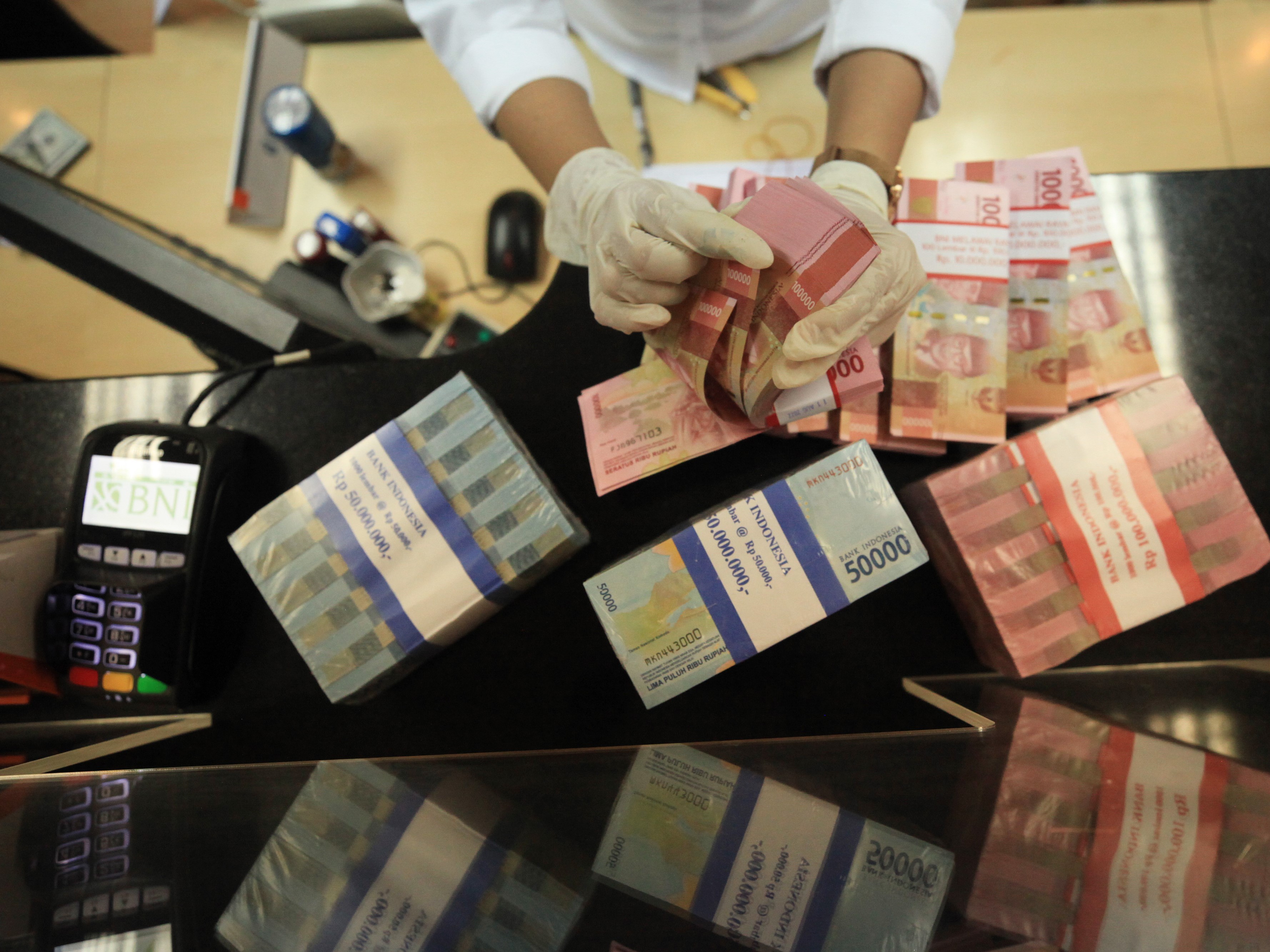 Petugas menghitung uang dolar AS dan rupiah di salah satu kantor cabang PT Bank Negara Indonesia (Persero) Tbk, KCU Melawai, Jakarta.
