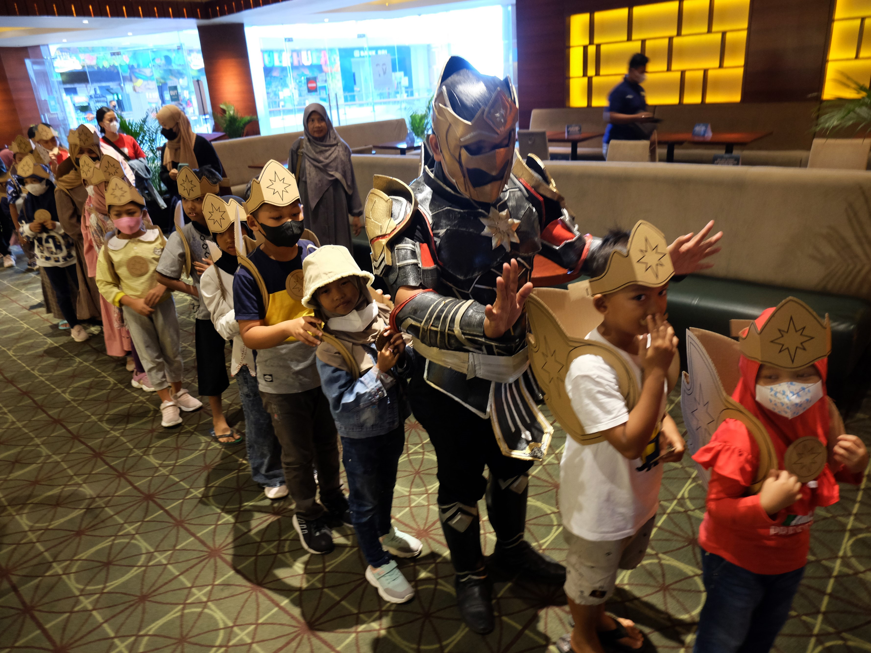 Relawan Super Isoman berkostum tokoh wayang Gatot Kaca milenial mengajak anak yatim untuk menonton film di bioskop.