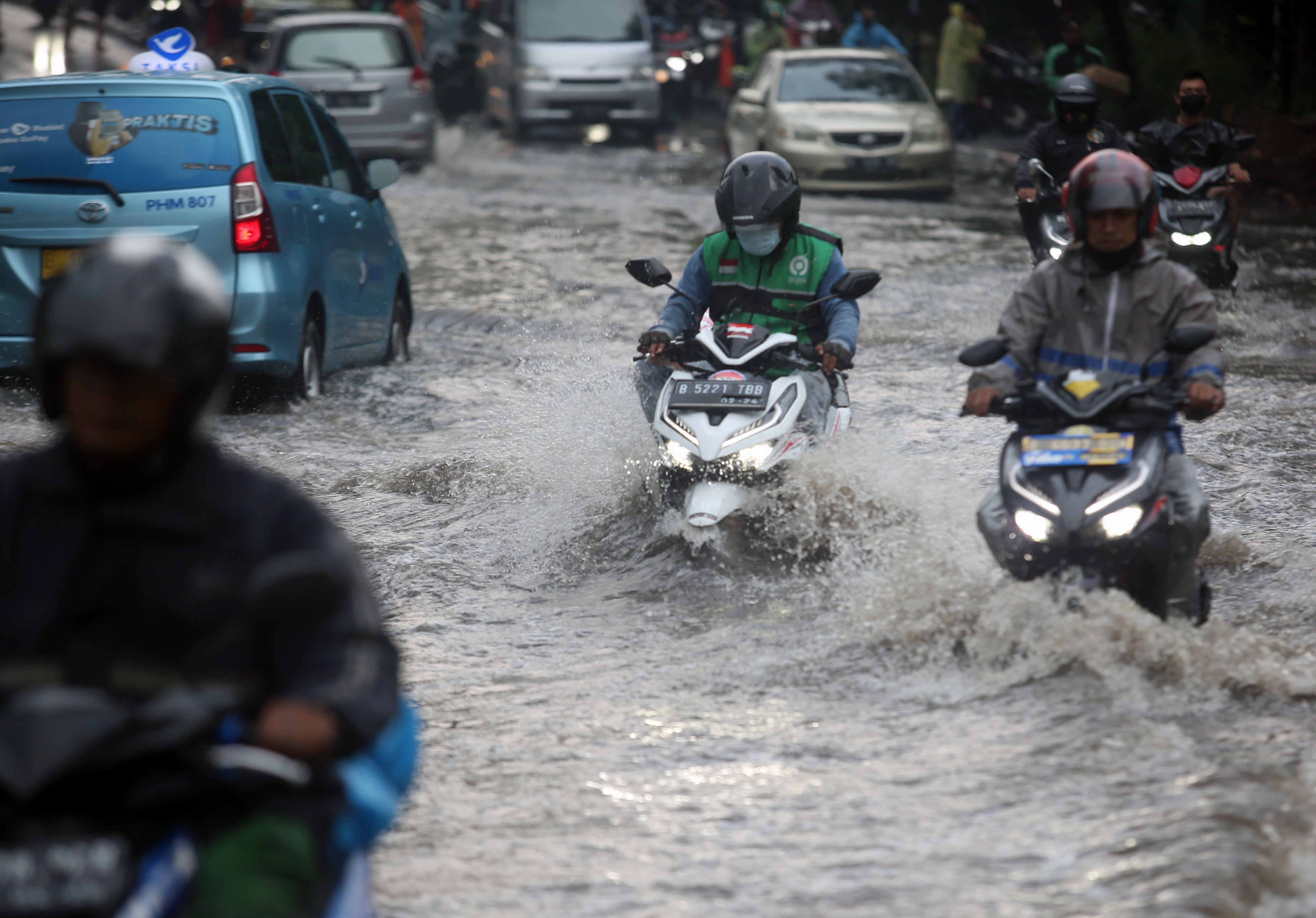 Pengendara motor menerobos banjir di jalan wilayah Jakarta.