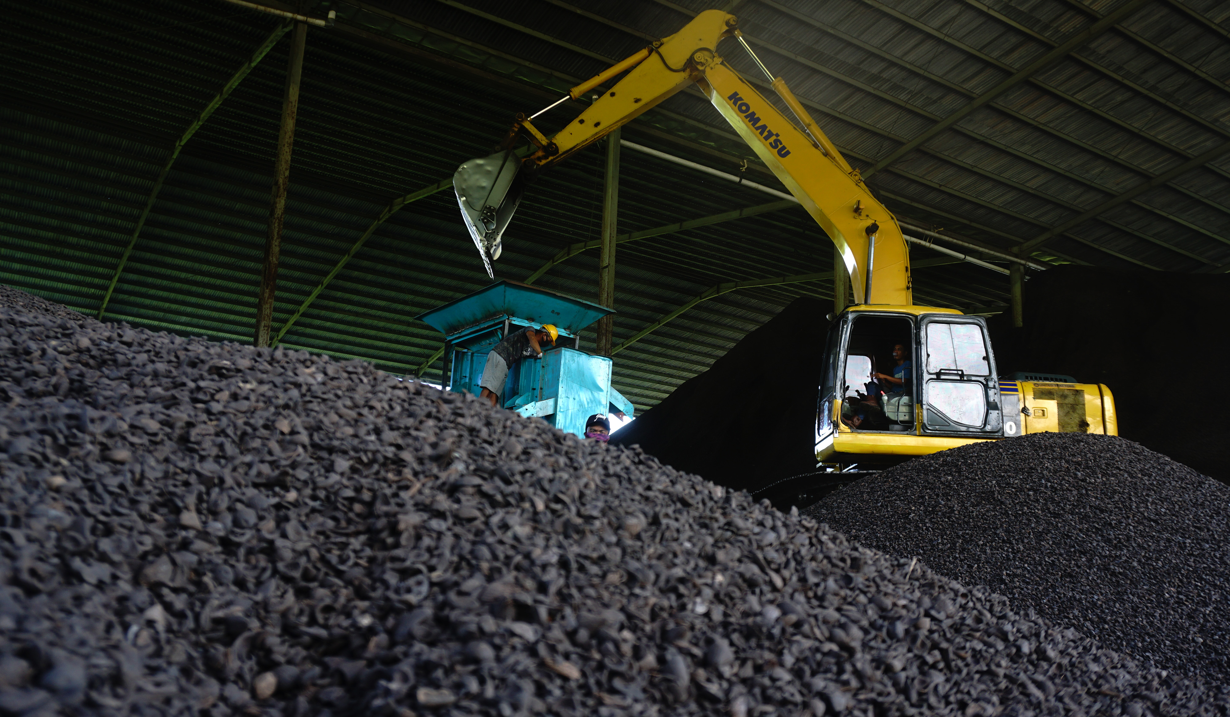 Pekerja dan alat berat menggiling cangkang sawit yang akan diekspor ke Japang di Pelabuhan Belang-belang , Mamuju, Sulawesi Barat.