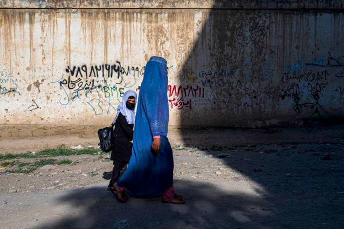 Seorang perempuan mengenakan burqa bersama anaknya melintas di Kota Kabul, Afghanistan.