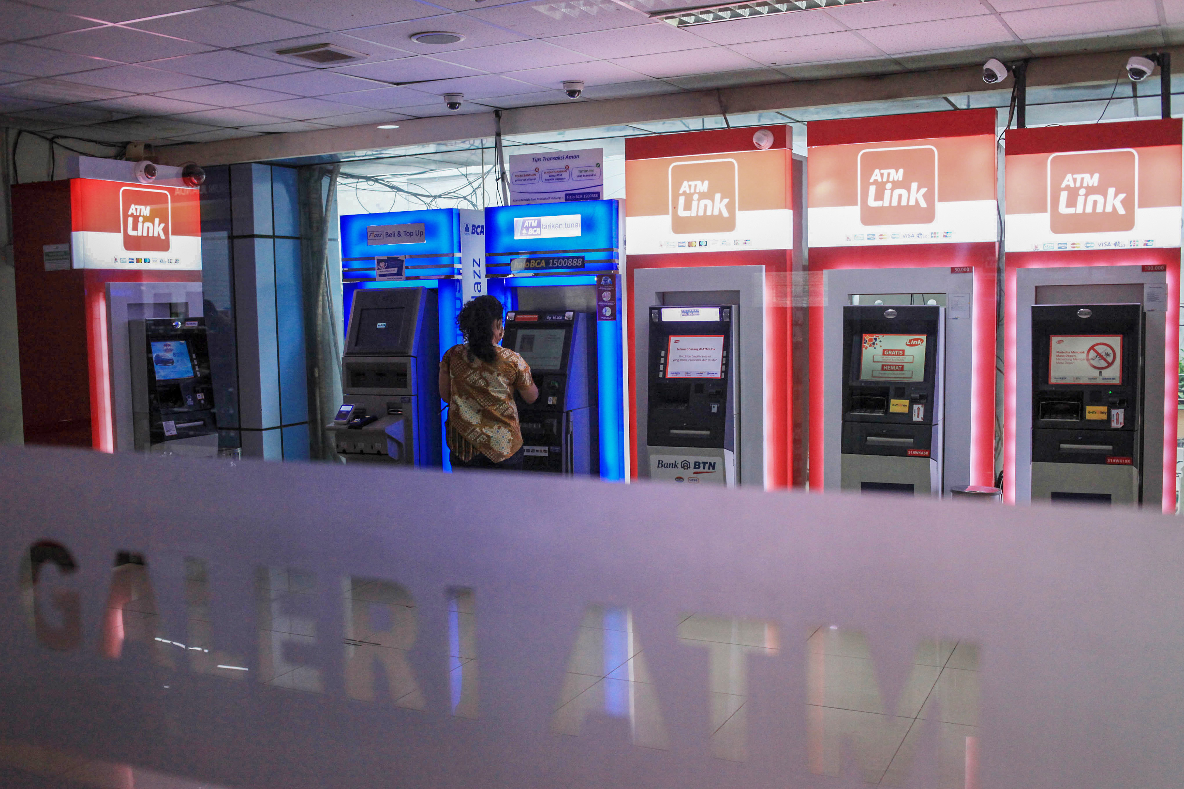 Warga bertansaksi melalui mesin anjungan tunai mandiri (ATM) di Galeri ATM Stasiun KA Juanda, Jakarta.