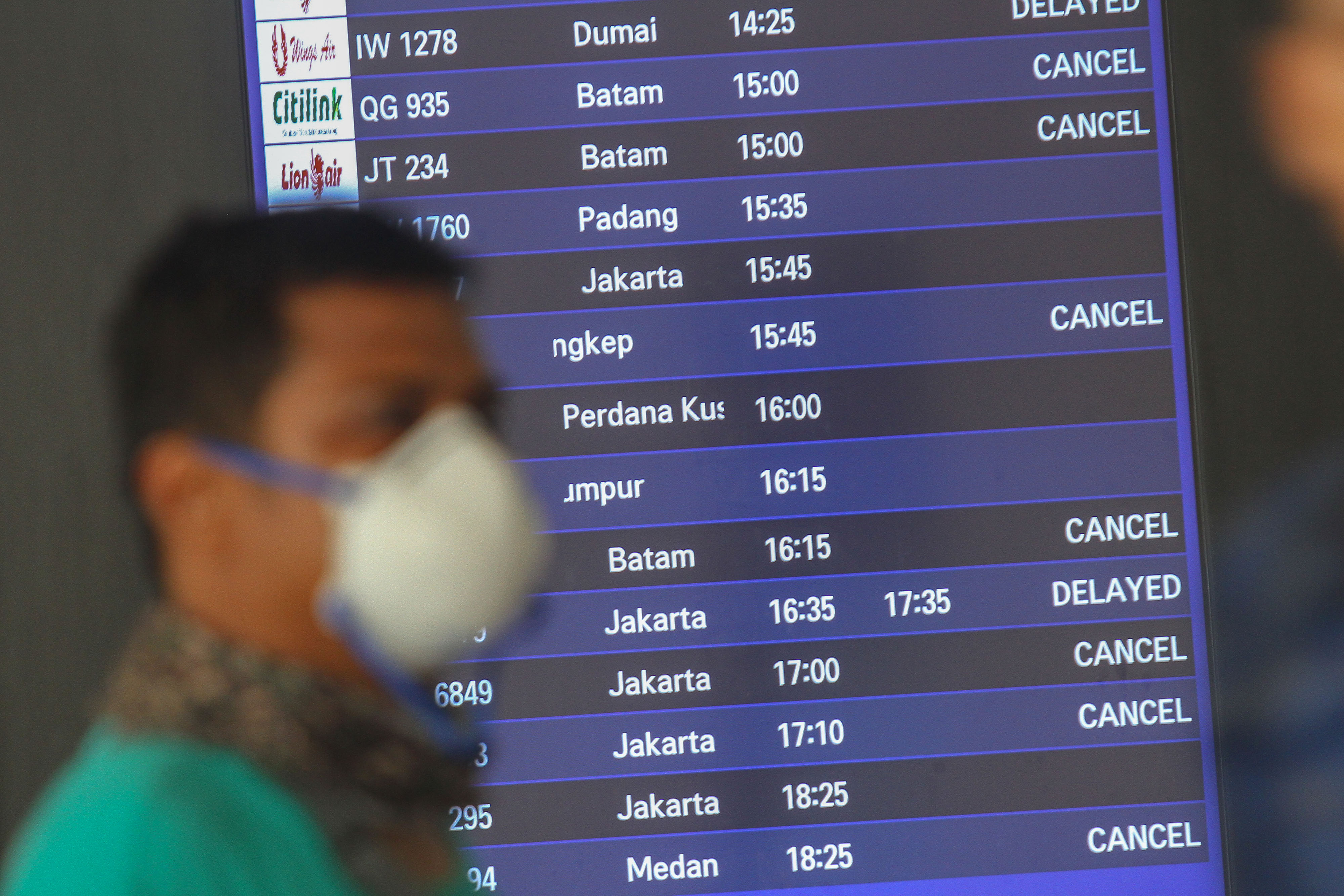 Seorang penumpang berjalan di depan layar informasi Bandara Sultan Syarif Kasim II Pekanbaru, Riau.