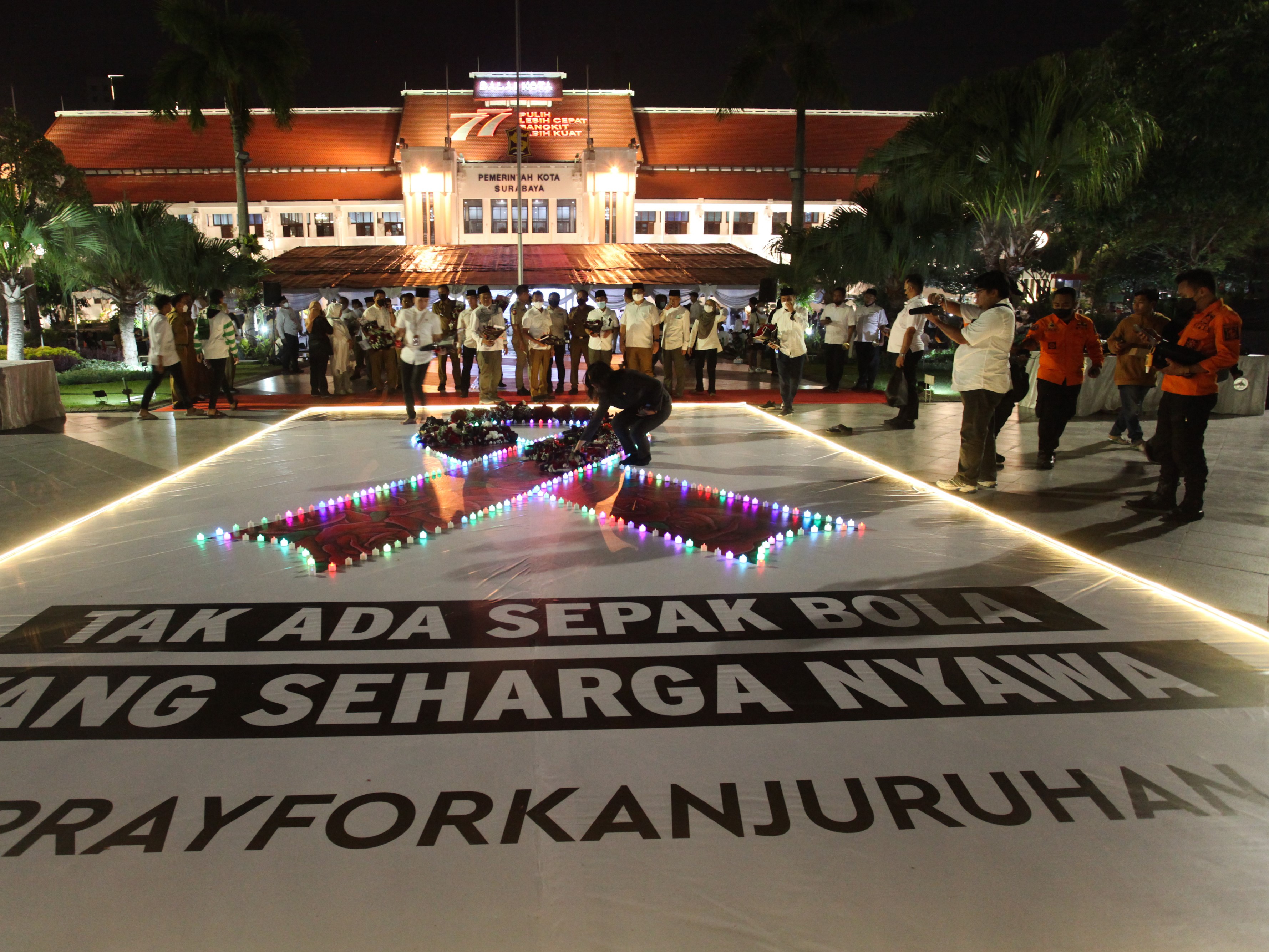 Warga meletakkan bunga saat doa bersama di Balai Kota Surabaya, Jawa Timur, Selasa (4/10/2022) malam.