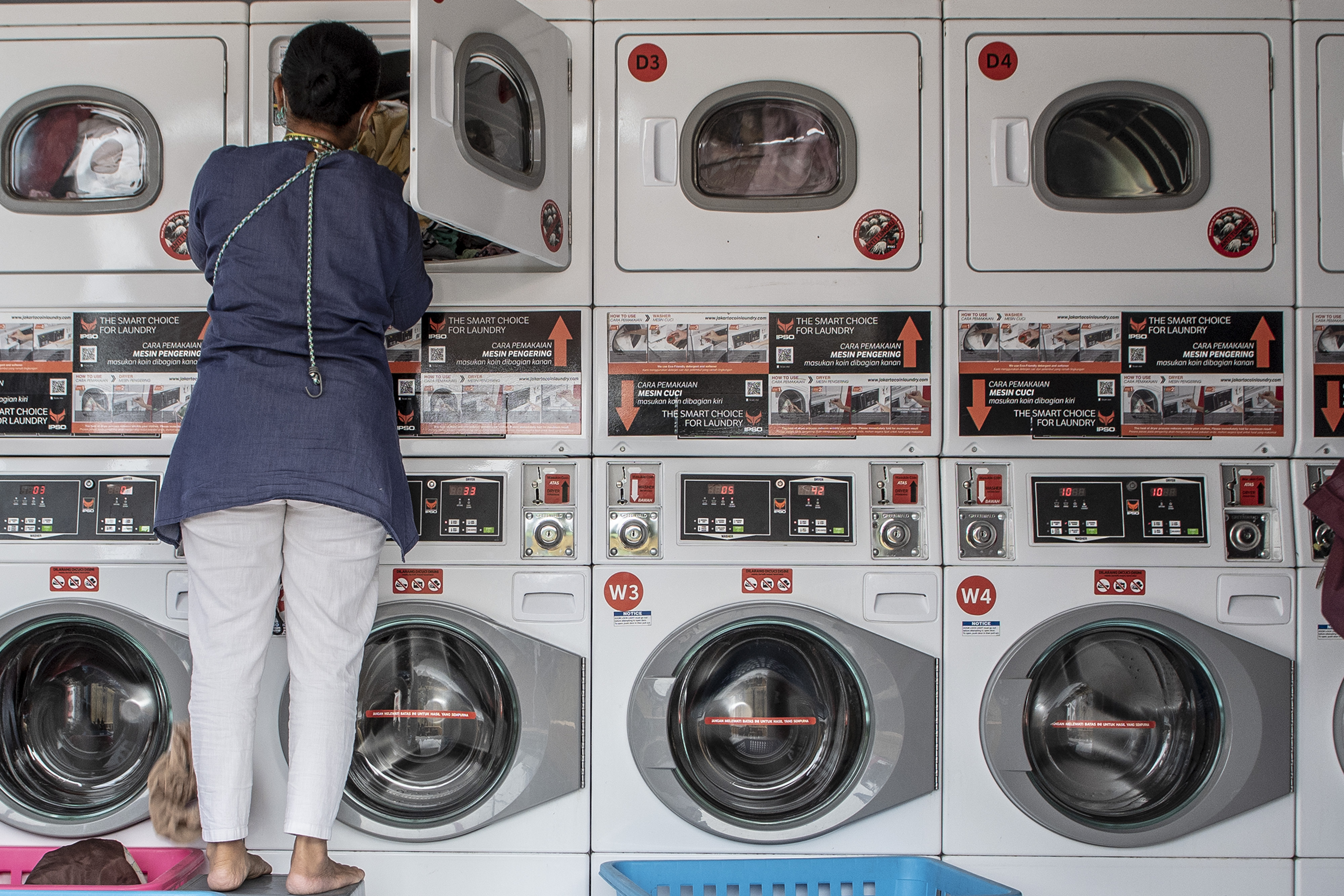 Warga menggunakan mesin cuci di tempat jasa pencucian pakaian di Tangerang, Banten.
