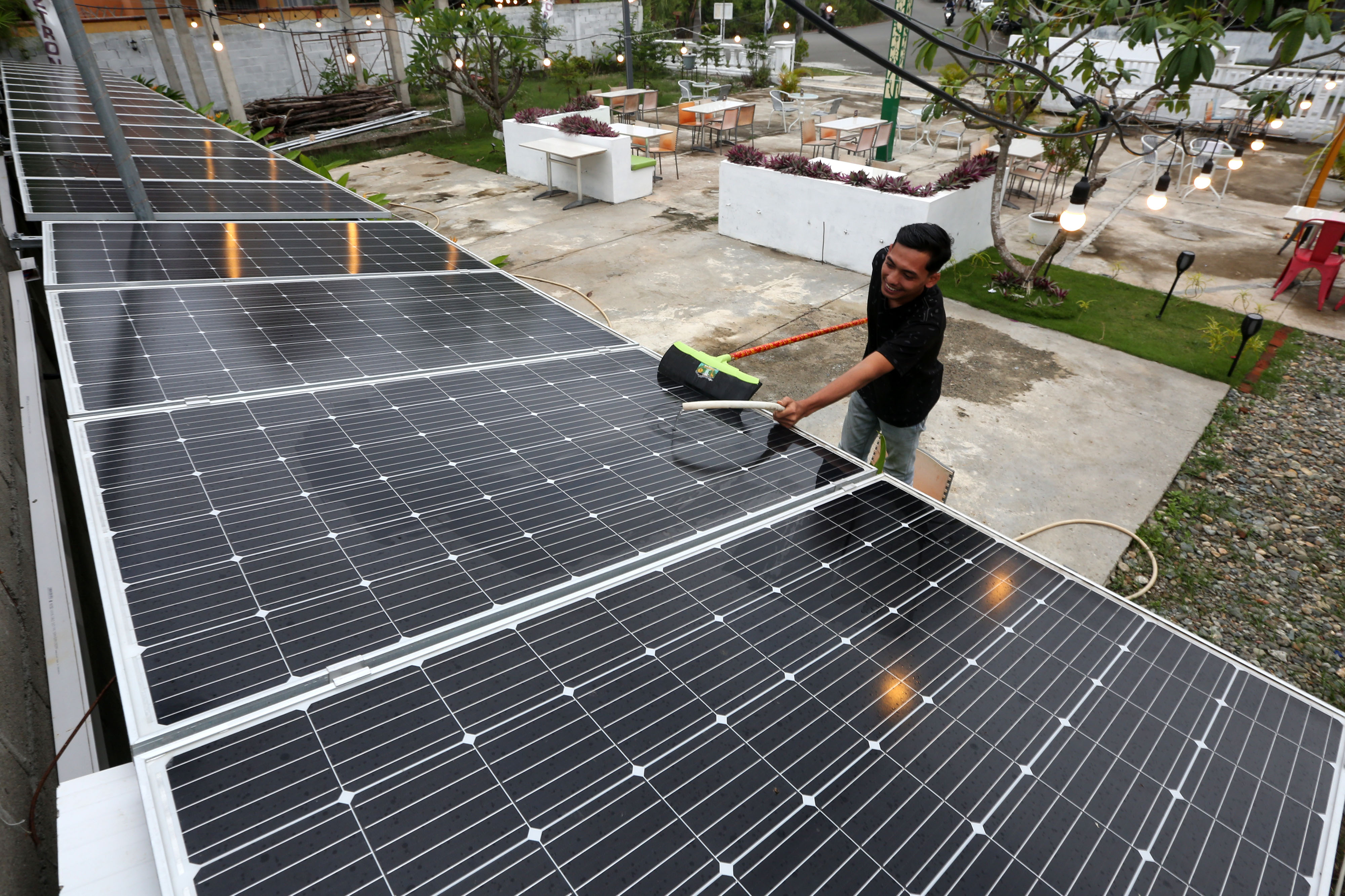 Pekerja membersihkan panel surya di Twins Caffe, Banda Aceh, Aceh.