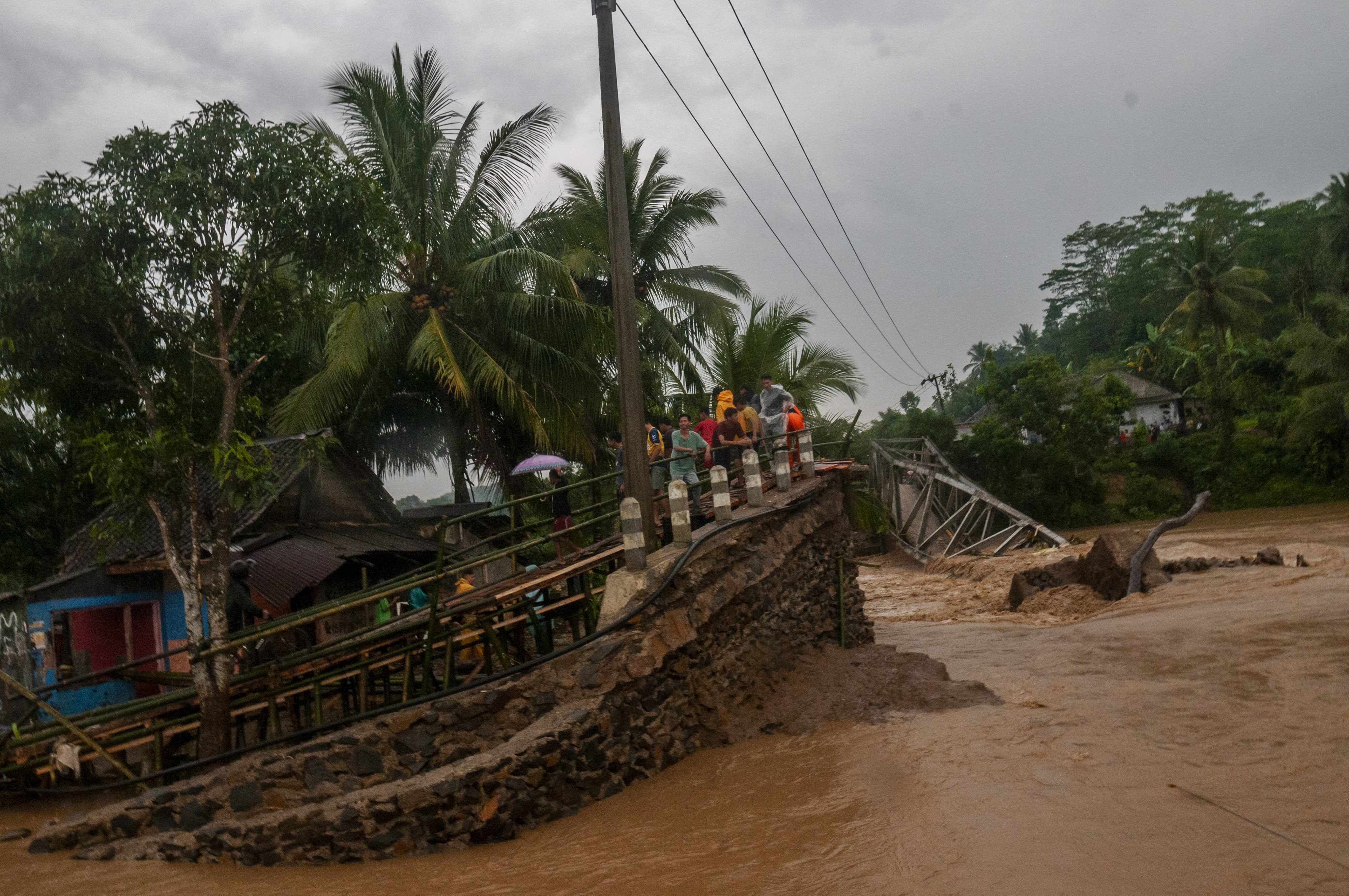 Warga melihat kondisi jembatan yang terputus akibat diterjang banjir bandang di Sukajaya, Lebak, Banten, Selasa (11/10).