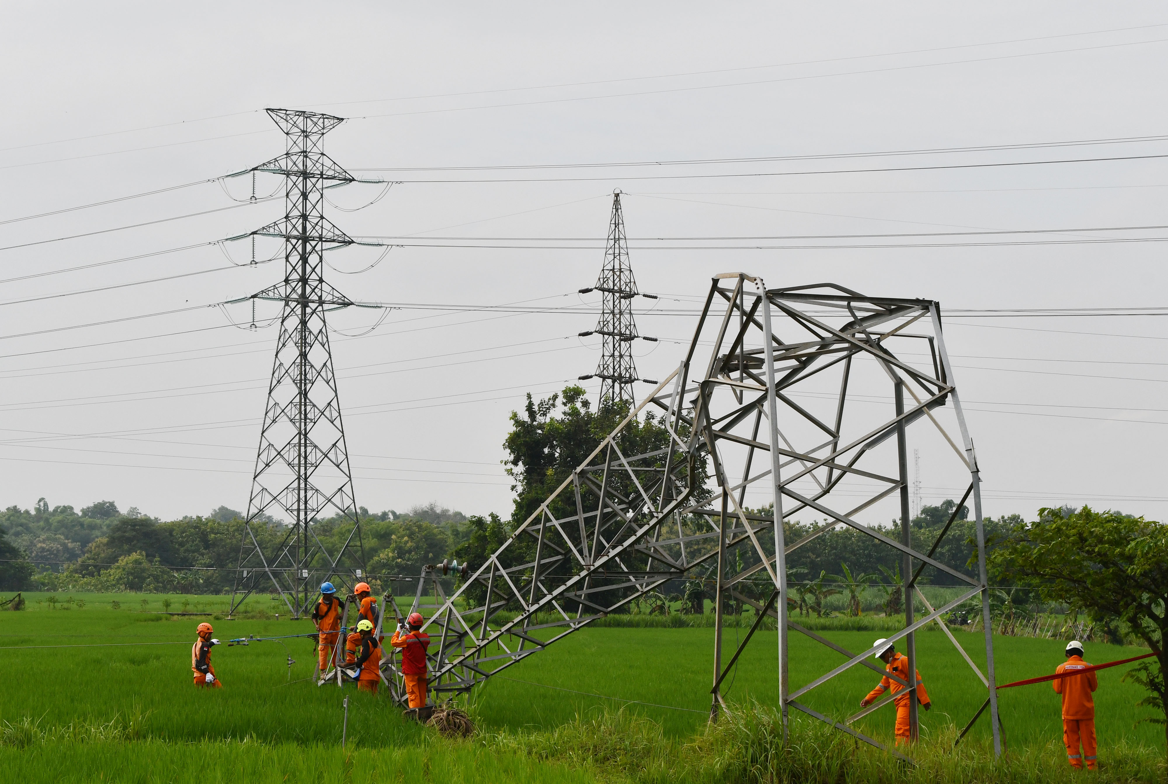 Sejumlah petugas berusaha memperbaiki tower listrik yang rubuh akibat bencana angin kencang.