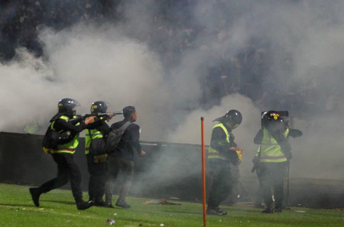 Aparat keamanan menembakkan gas air mata untuk menghalau suporter yang masuk lapangan usai pertandingan sepak bola BRI Liga 1.