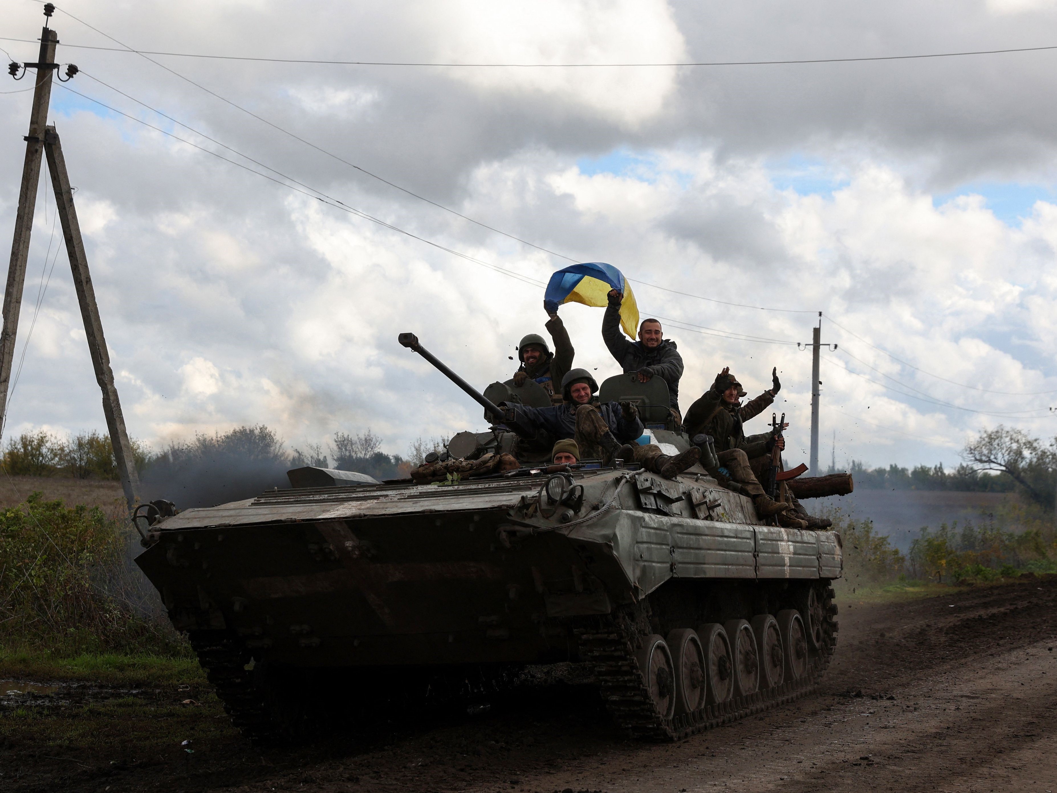 Tentara Ukraina mengibarkan bendera nasional di atas kendaraan lapis baja personel di jalan dekat Lyman, Donetsk, Selasa (4/10).