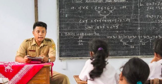 Guru sedang mengajar di muka kelas.