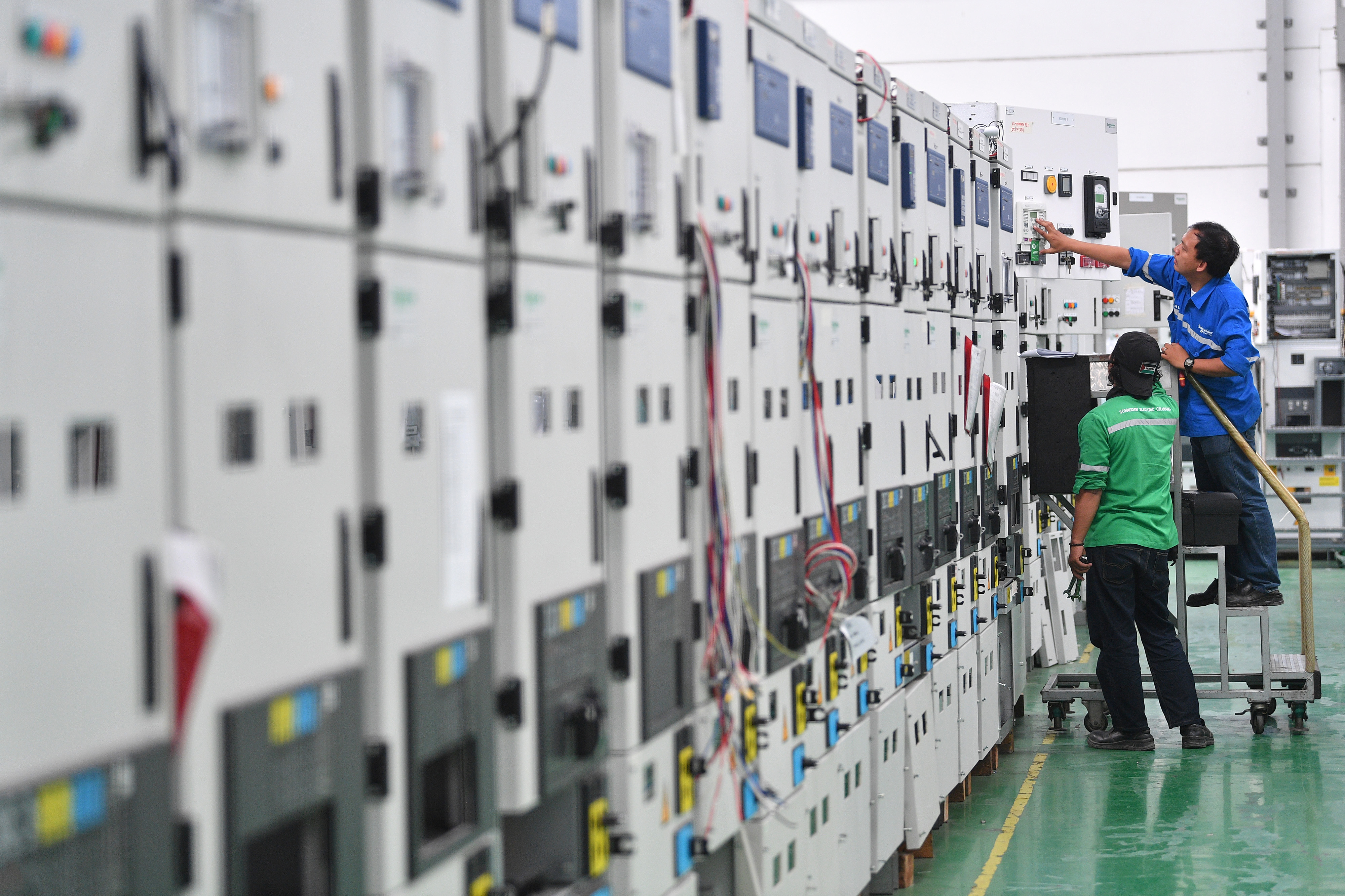 Pekerja memeriksa panel listrik yang diproduksi di pabrik pintar Schneider Electric Indonesia, Cikarang, Jawa Barat.