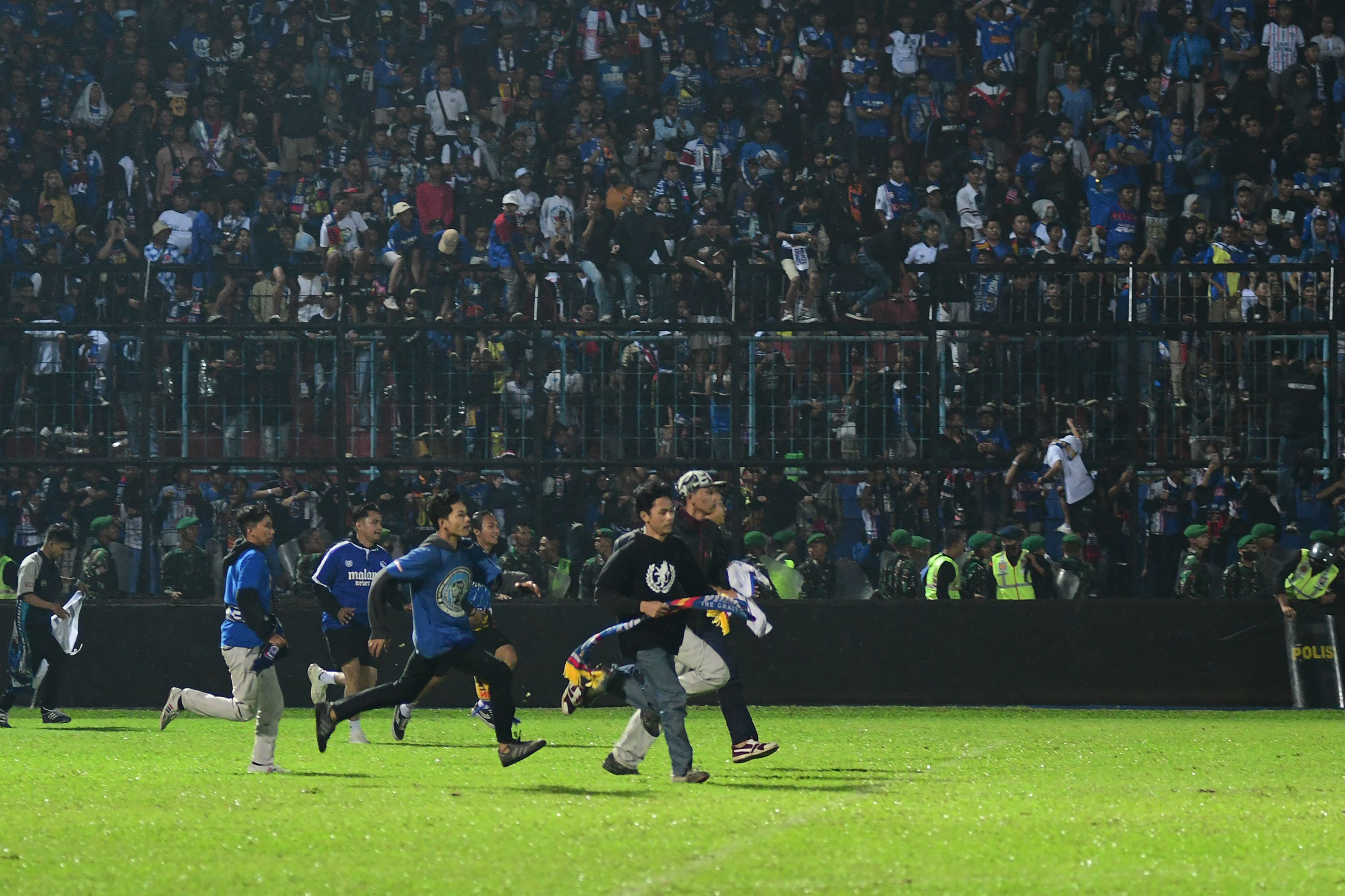 Sejumlah suporter Arema FC berlari ke tengah lapangan usai laga melawan Persebaya di Stadion Kanjuruhan, Malang, Sabtu (1/10) malam.