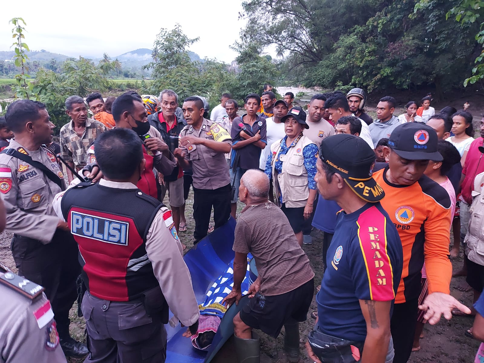 Tim SAR dari BPBD, polisi, dan warga mengevakuasi anak yang tewas terseret banjir di Kabupaten Timor Tengah Utara, NTT, Senin (31/10).