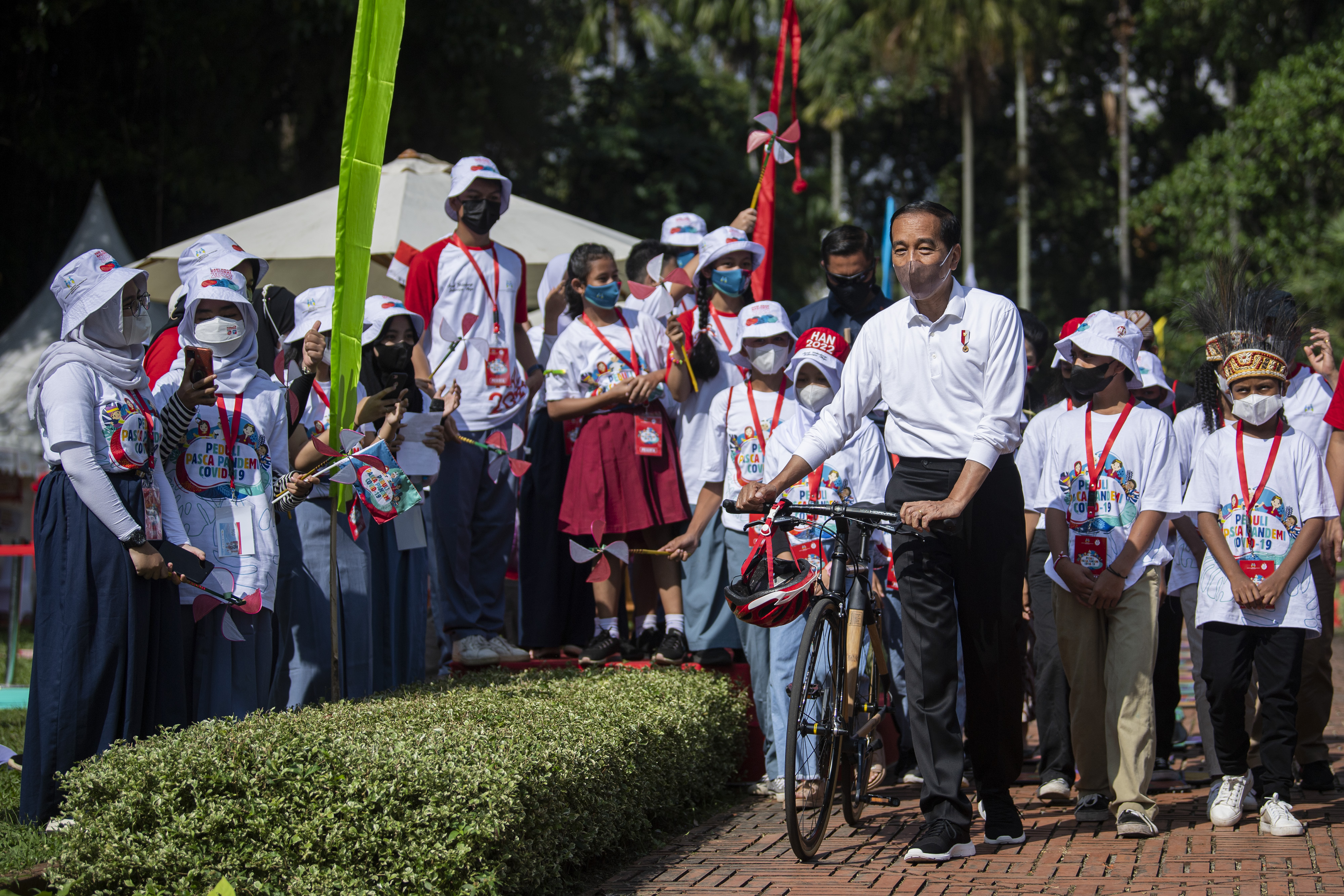 Presiden Jokowi menuntun sepedanya saat menghadiri acara peringatan Hari Anak Nasional.