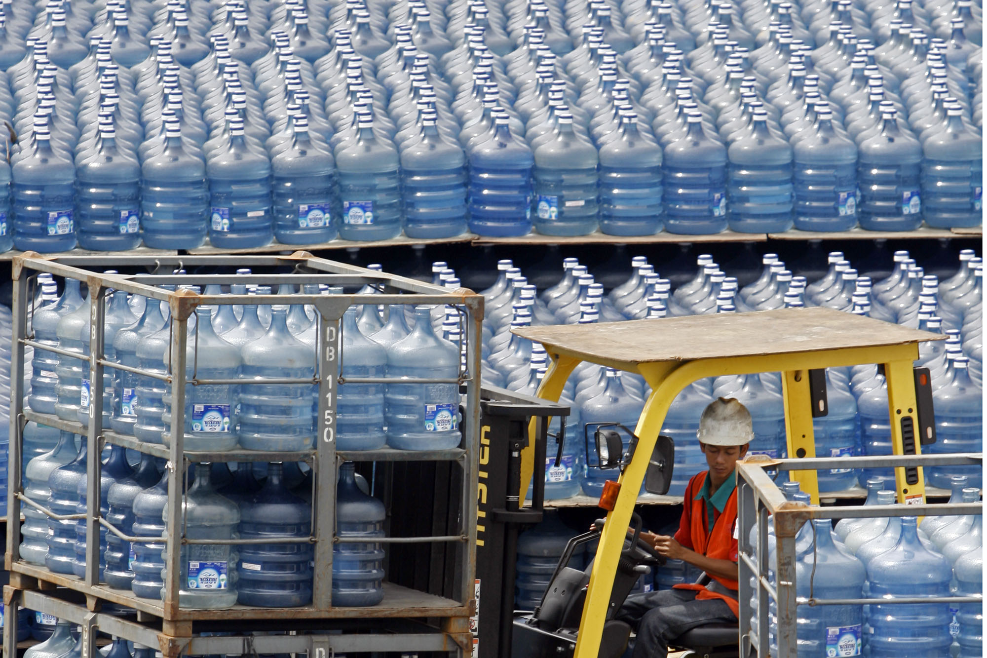 Pekerja mengatur tumpukan galon air minum isi ulang di pusat pengisian di kawasan Kalibata, Jakarta Selatan.