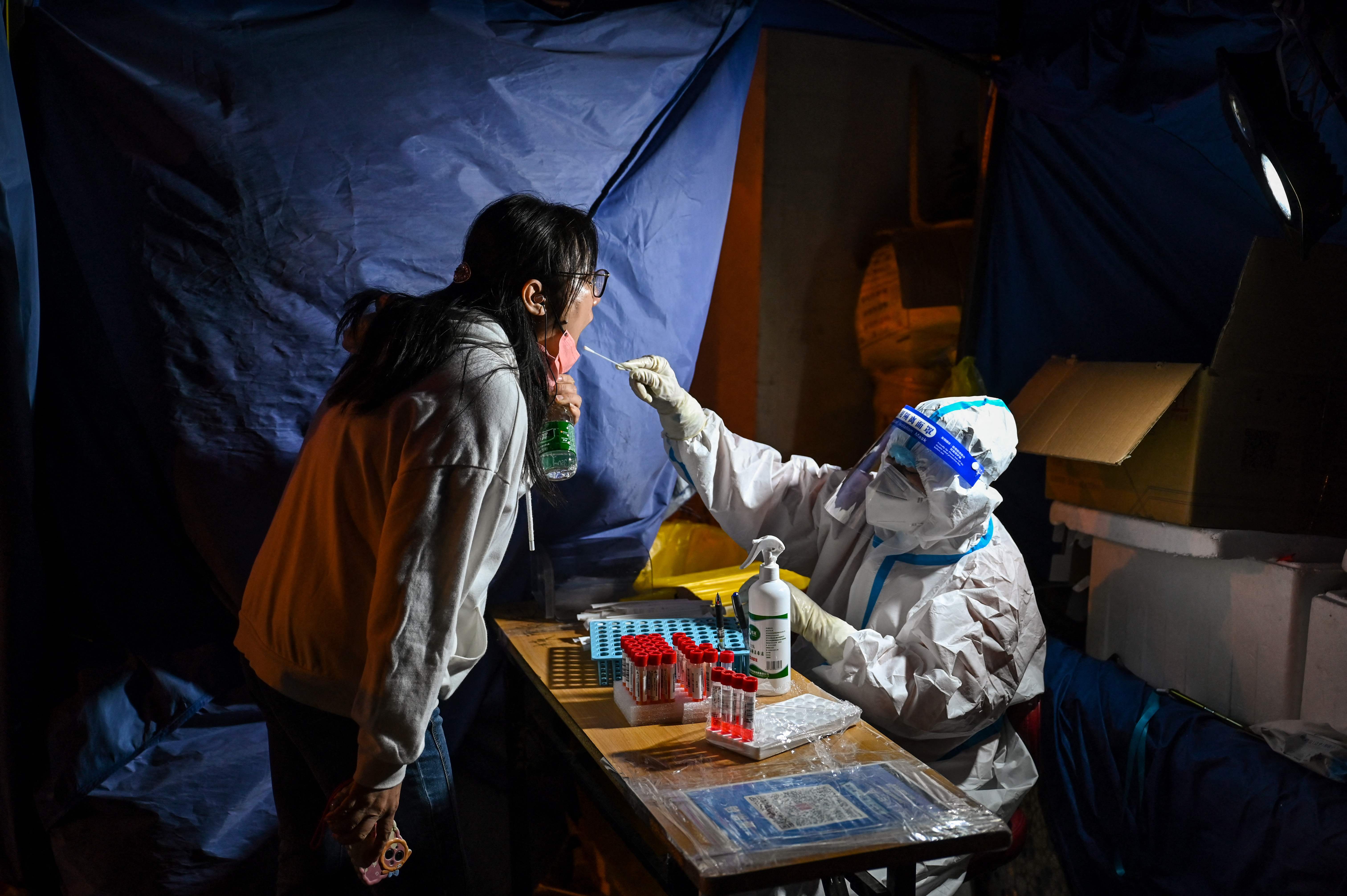 Petugas medis melakukan tes swab terhadap warga di wilayah Shanghai, Tiongkok.