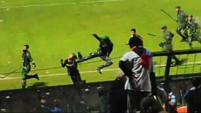 Seorang anggota TNI melakukan tendangan 'kung fu' kepada suporter Aremania saat terjadi kerusahan di Stadion Kanjuruhan, Malang. 