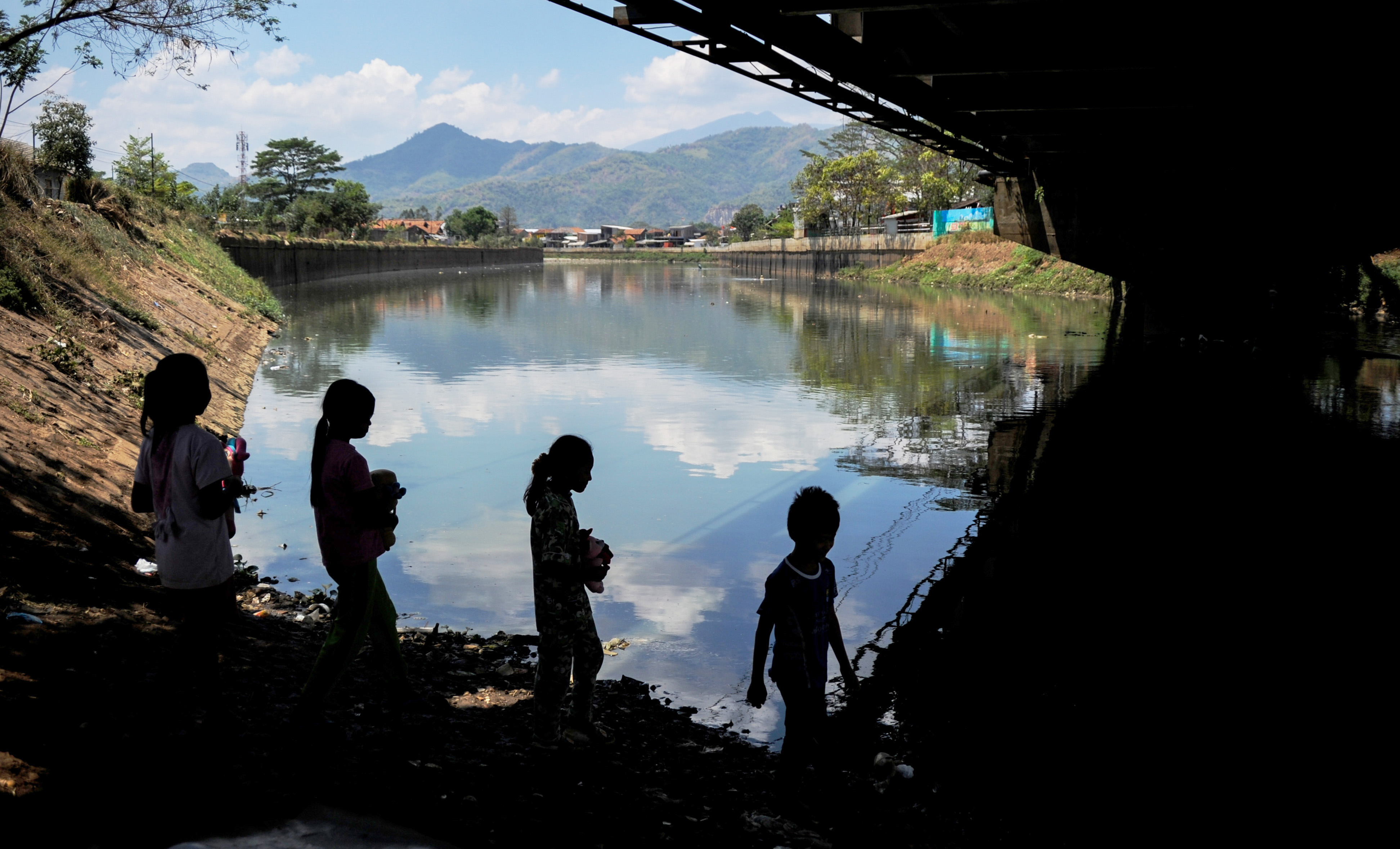 Potret sejumlah anak bermain di bantaran sungai.