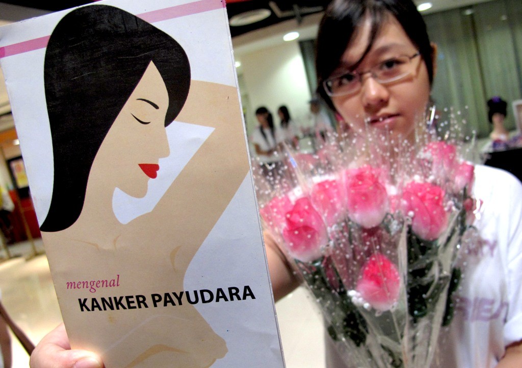 Seorang perempuan memperlihatkan pamflet berisi informasi mengenai kanker payudara.
