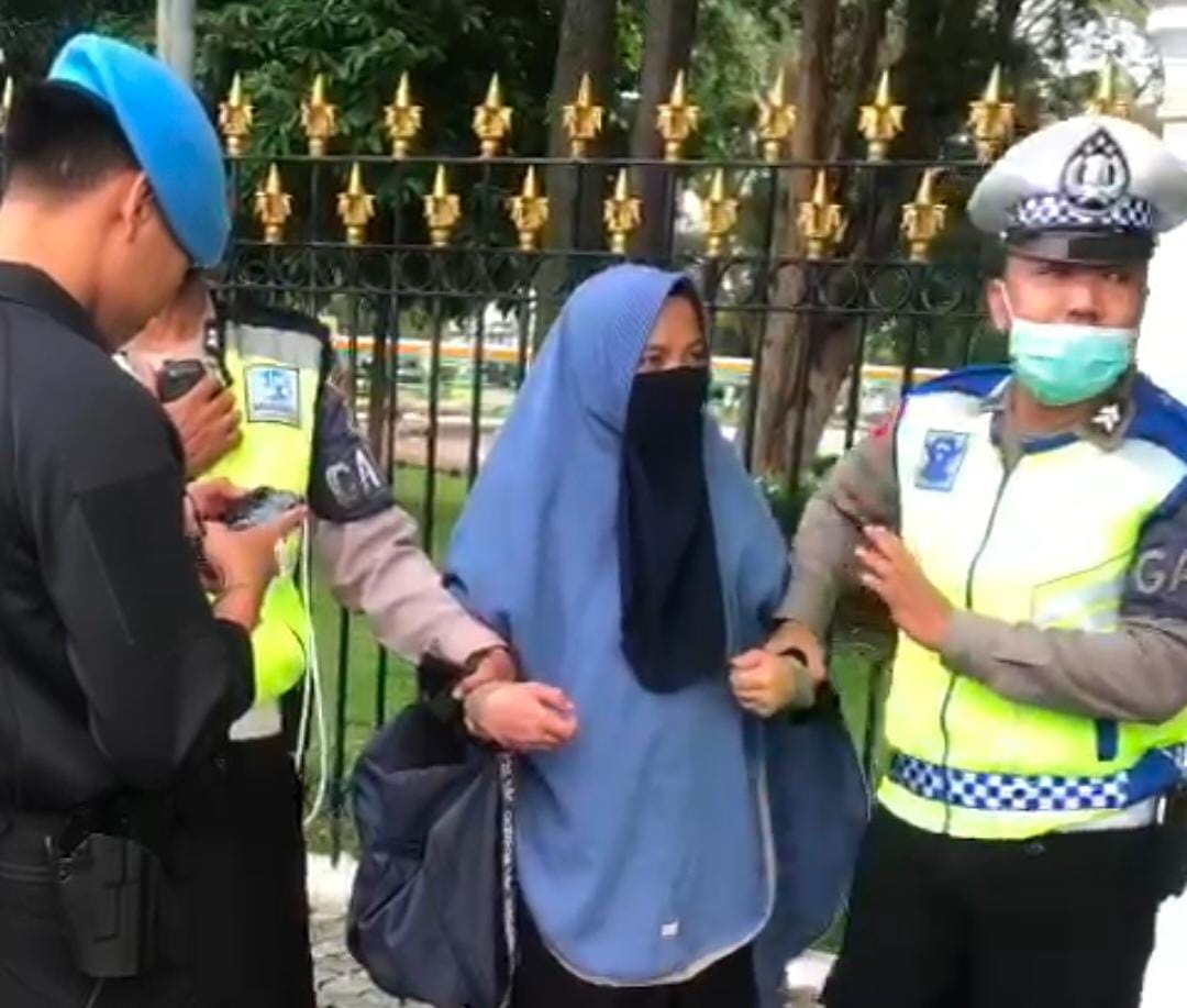 Polantas dari Polda Metro Jaya mengamankan seorang perempuan dengan senjata api jenis FN yang dibawanya di seberang Istana Negara.