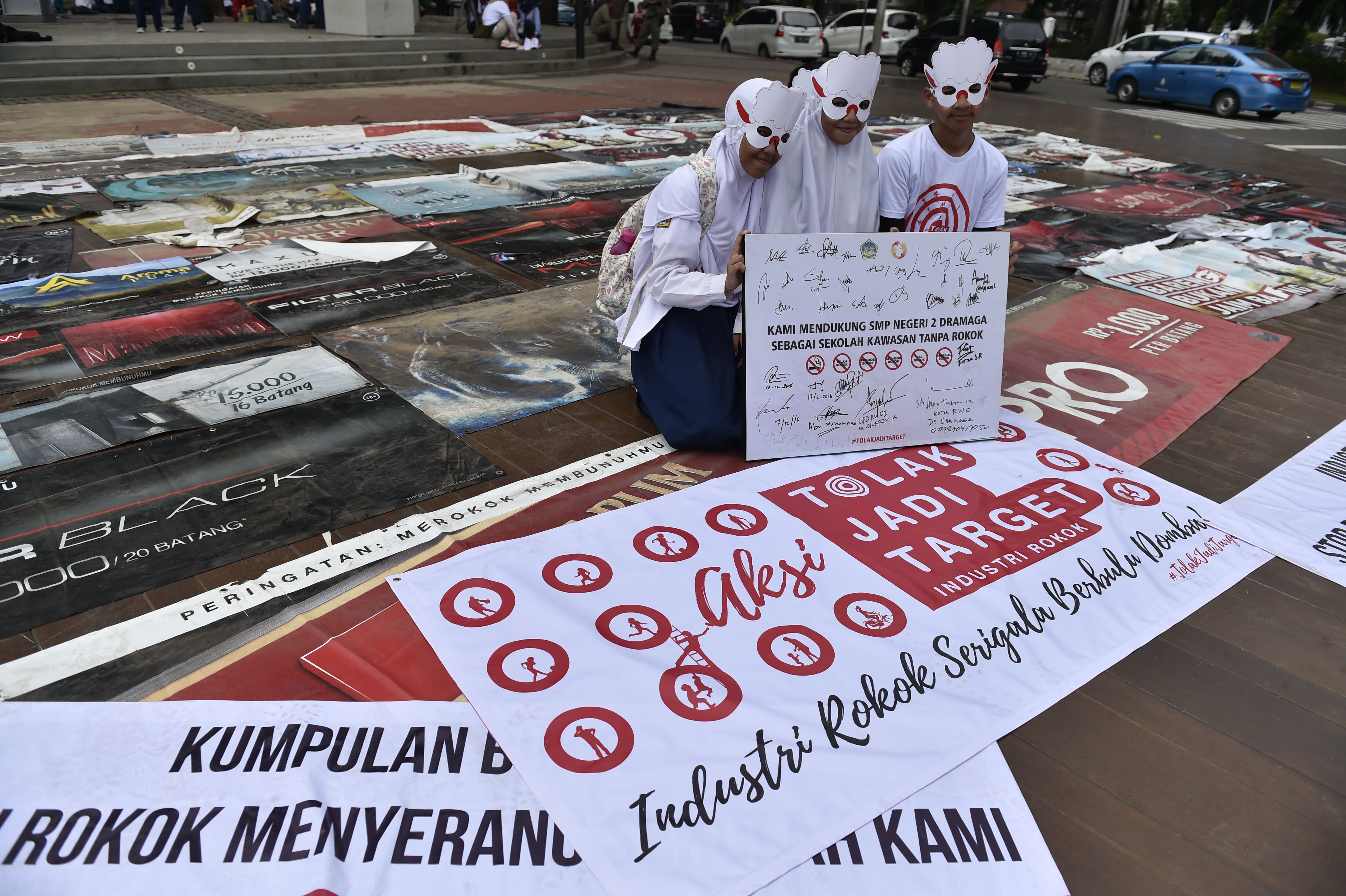 Tiga pelajar mengenakan topeng domba saat menggelar aksi #TolakJadiTarget iklan rokok di kawasan Silang Monas, Jakarta.