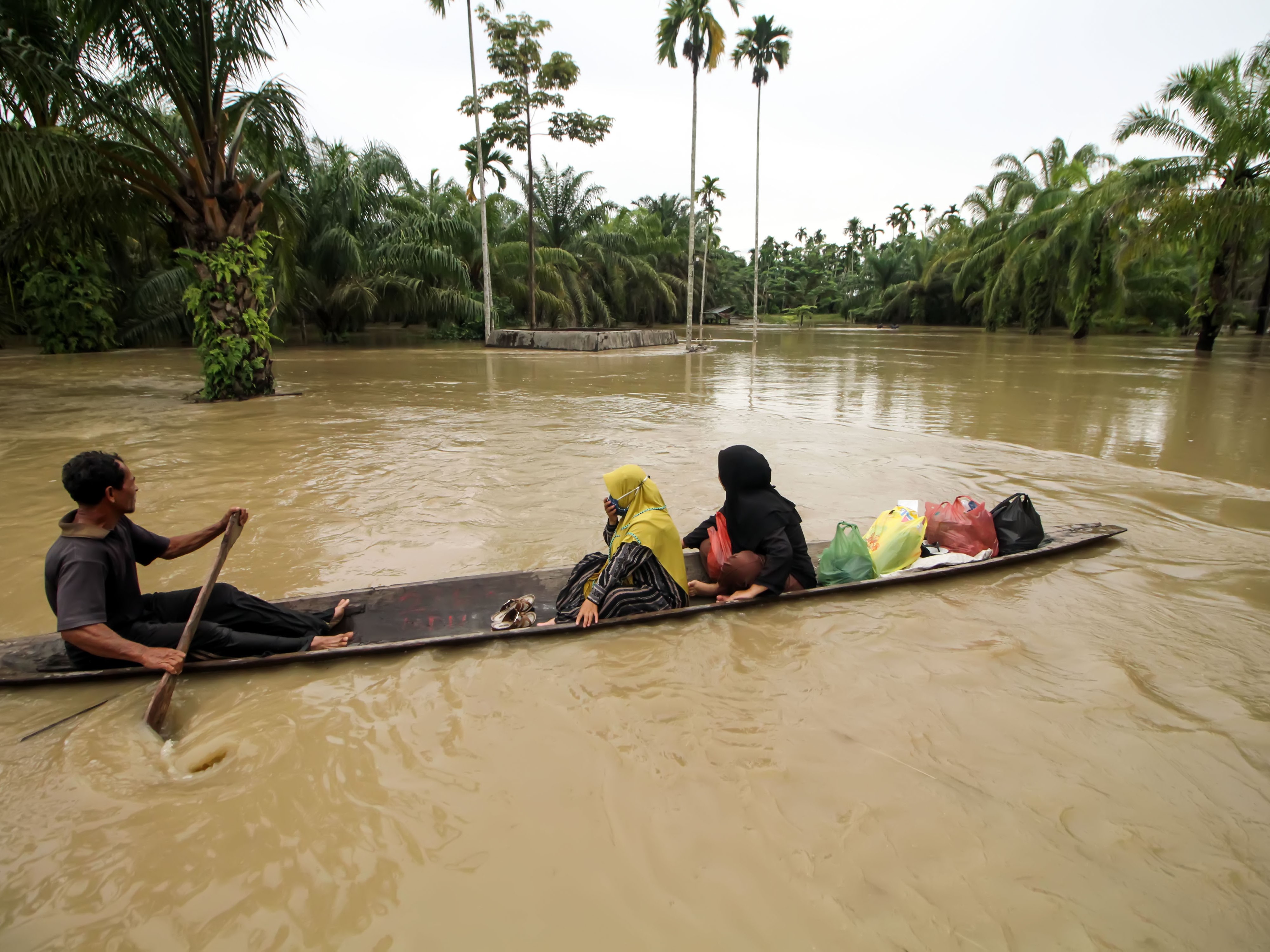 Warga melewati banjir dengan menggunakan perahu di Desa Mesjid Pirak, Kecamatan Matang Kuli, Aceh Utara, Aceh, Jumat (7/10/2022).