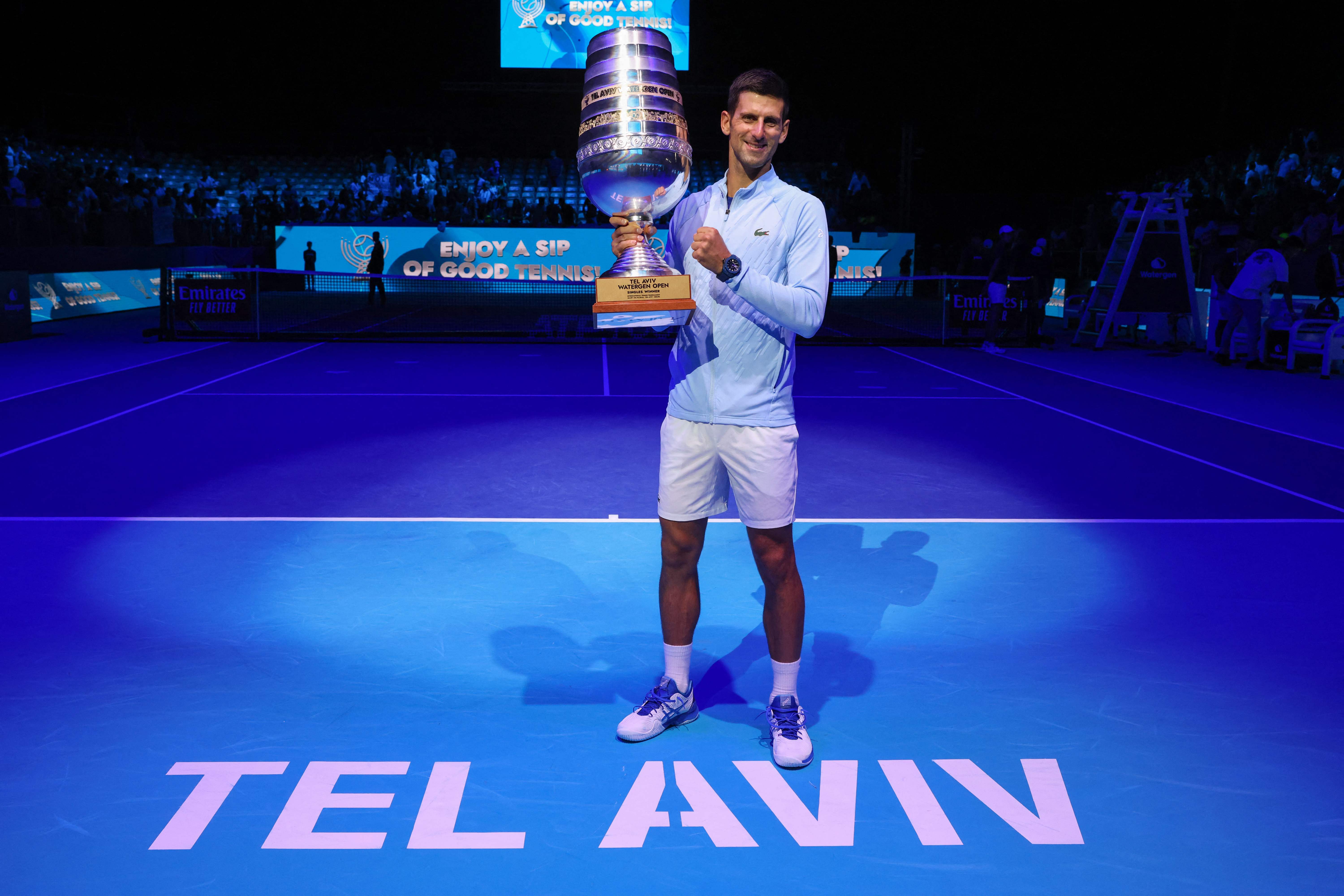 Petenis Serbia Novak Djokovic mengangkat trofi yang diraihnya pada Tel Aviv Watergen Open 2022 di Israel, Minggu (2/10).