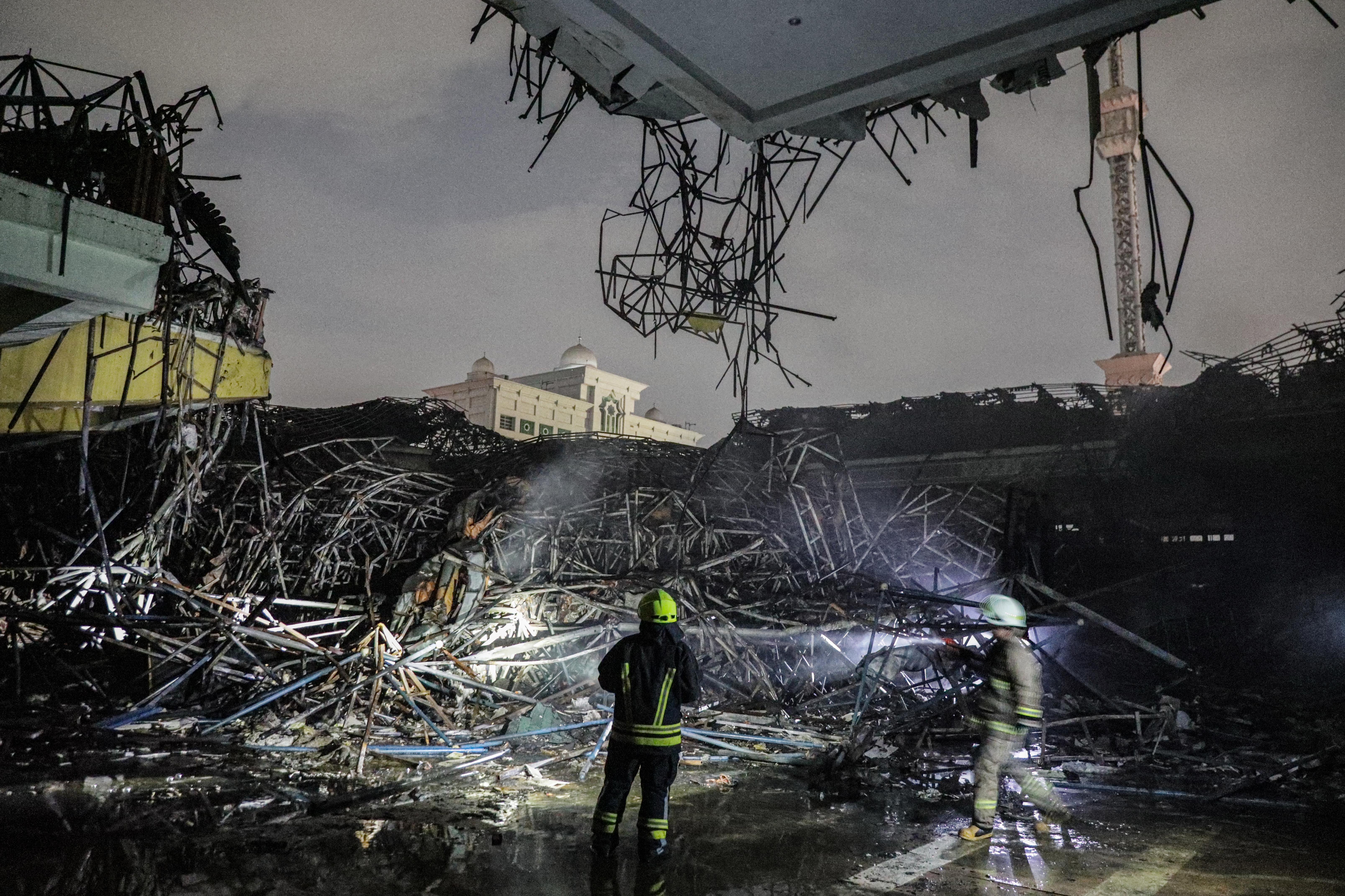Petugas melakukan proses pendinginan terhadap sisa kebakaran Masjid Jakarta Islamic Center.