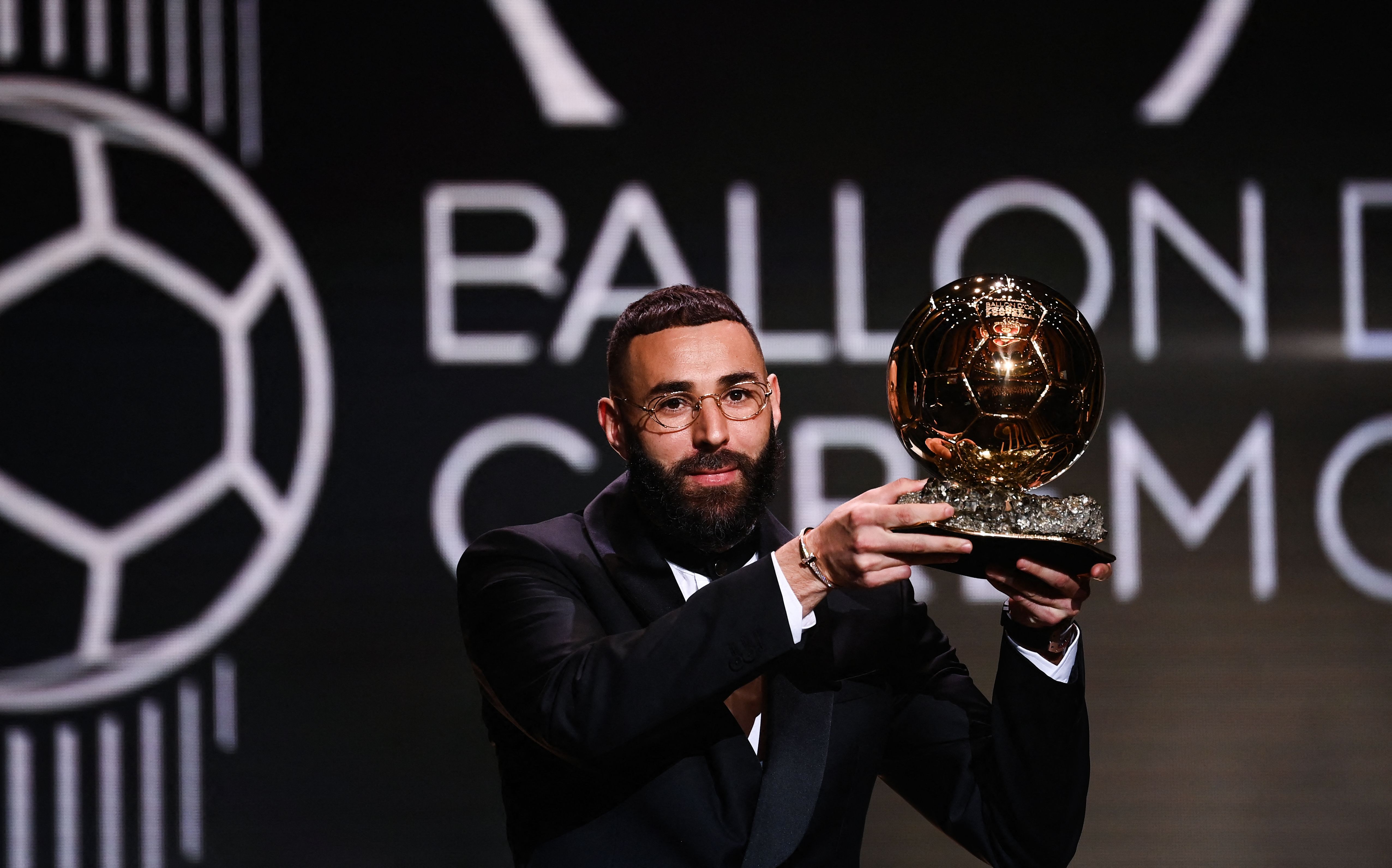 Penyerang Real Madrid Karim Benzema mengangkat trofi Ballon d'Or yang dimenangkannya.