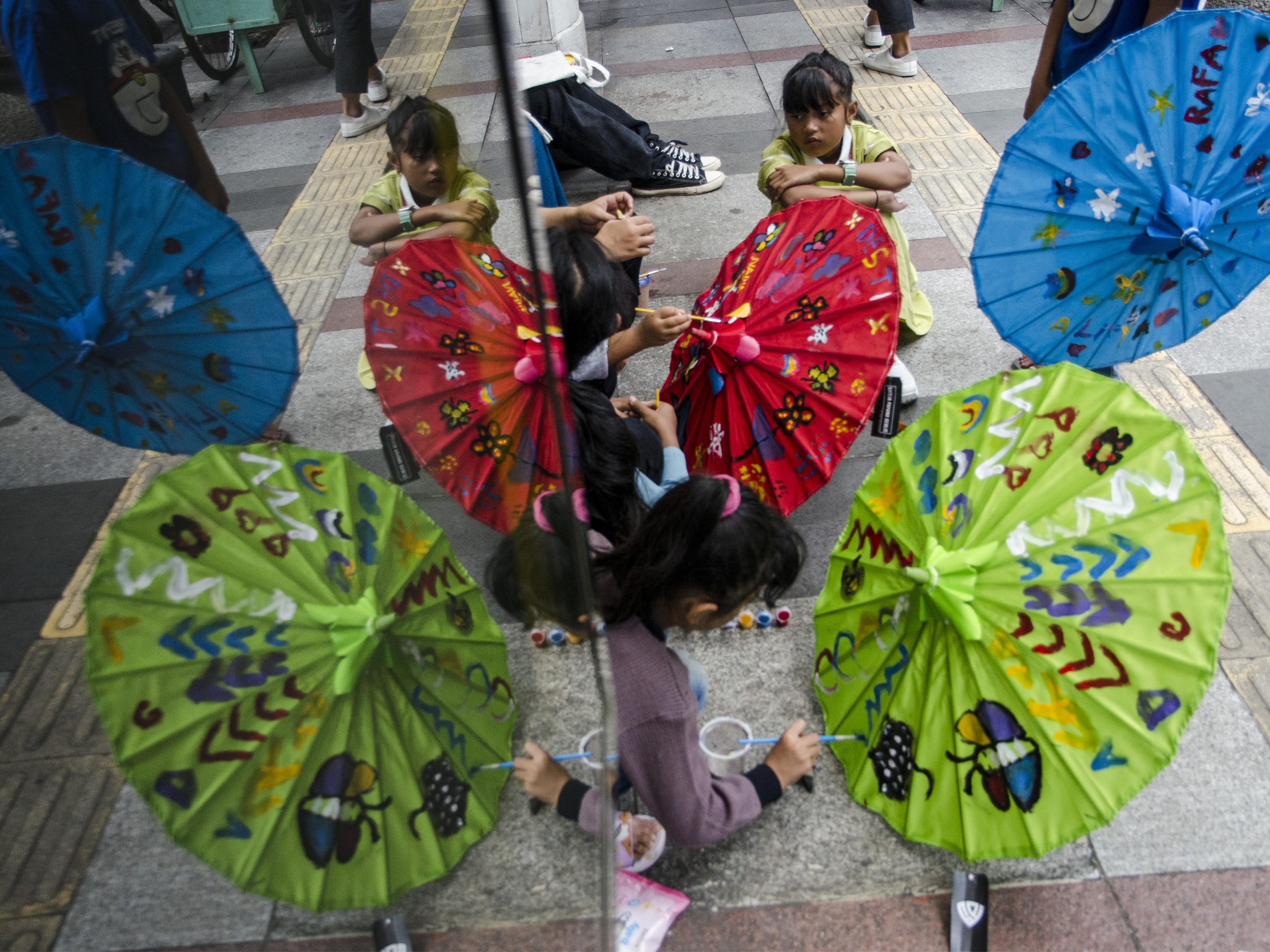 Anak-anak melukis di atas payung geulis di Braga, Bandung, Jawa Barat, Sabtu (29/10/2022).