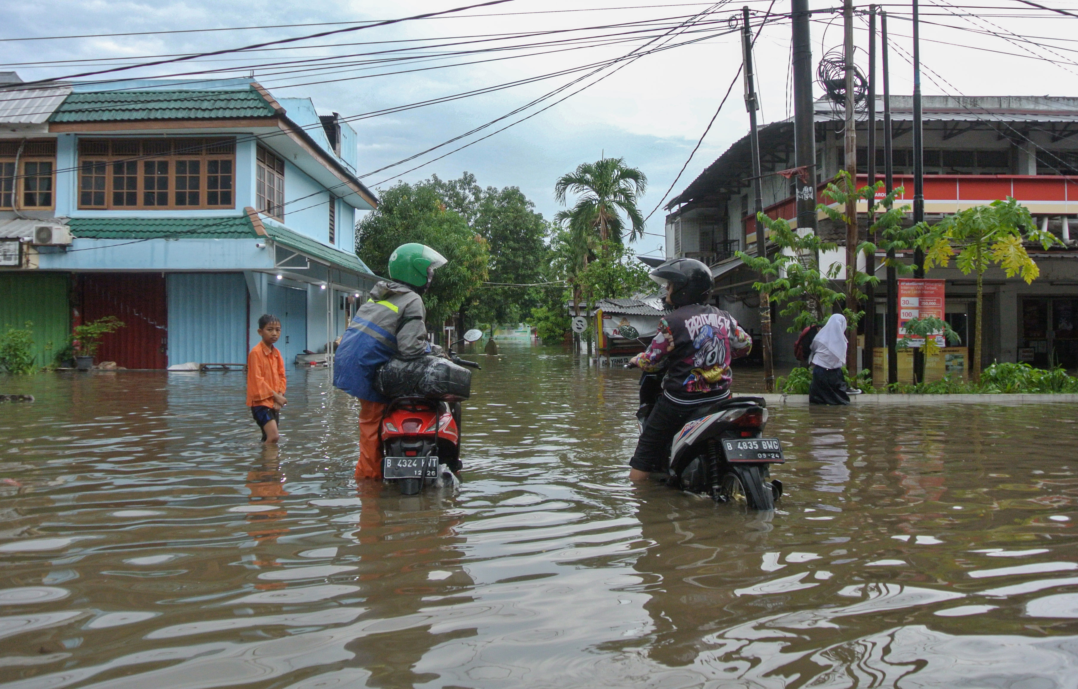 Dua pengendara motor terjebak di tengah genangan banjir di Taman Narogong Indah, Bekasi, Jawa Barat, Jumat (7/10/2022). 