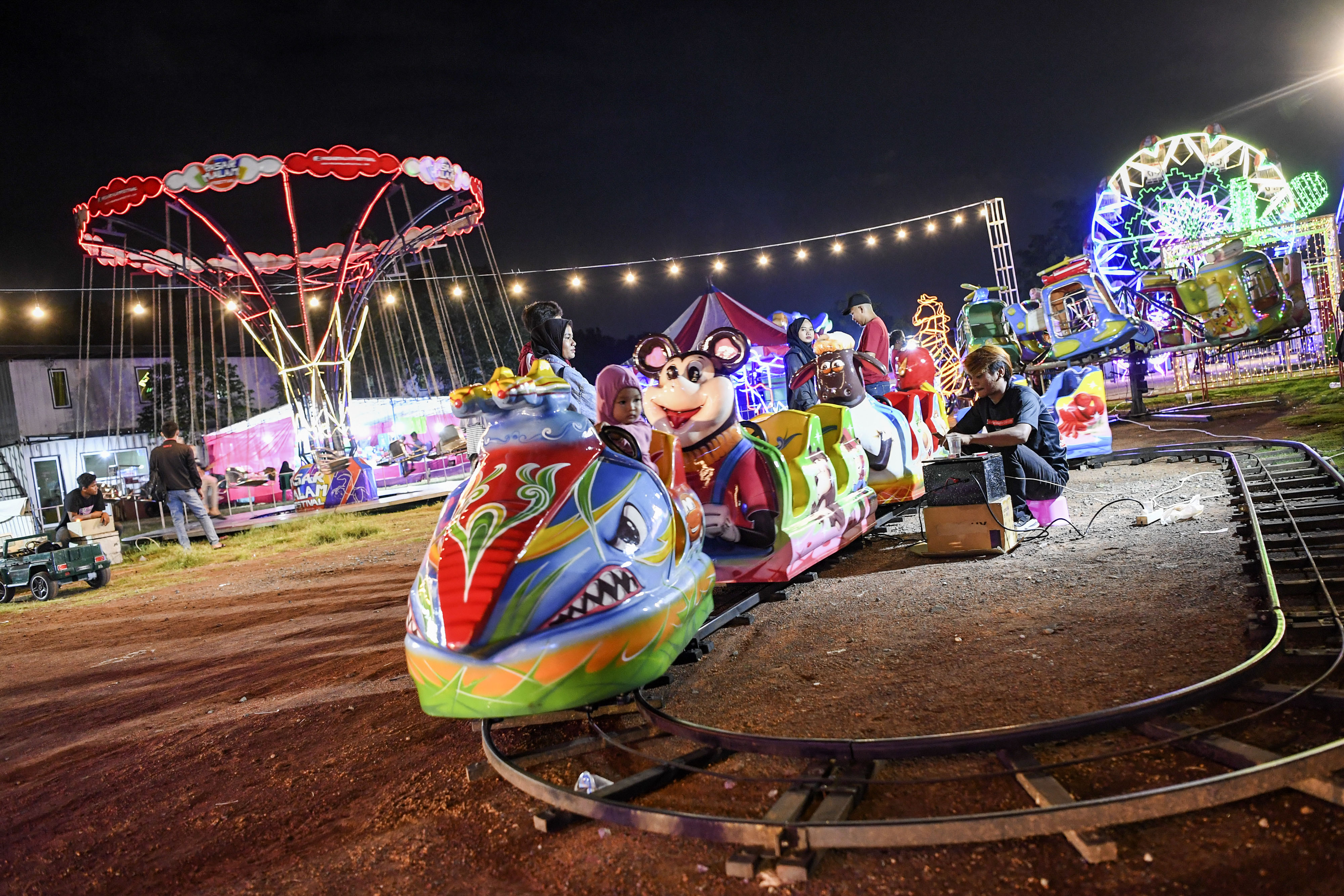 Sejumlah anak menaiki kereta mainan di wahana pasar malam kawasan Rorotan, Cilincing, Jakarta Utara.
