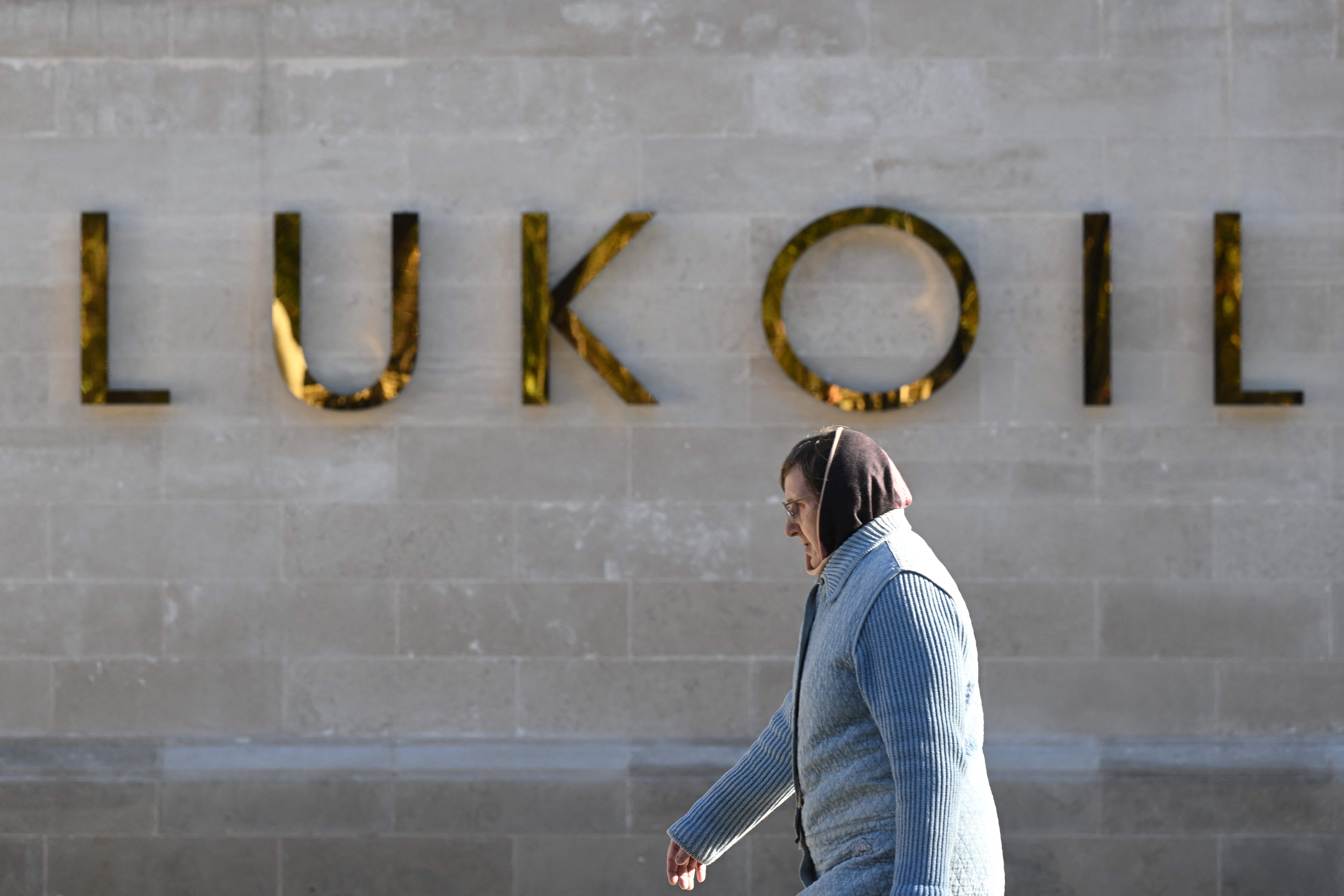 Seorang wanita berjalan melewati kantor pusat produsen minyak Rusia Lukoil di Moskow, Rusia, Senin (10/10).
