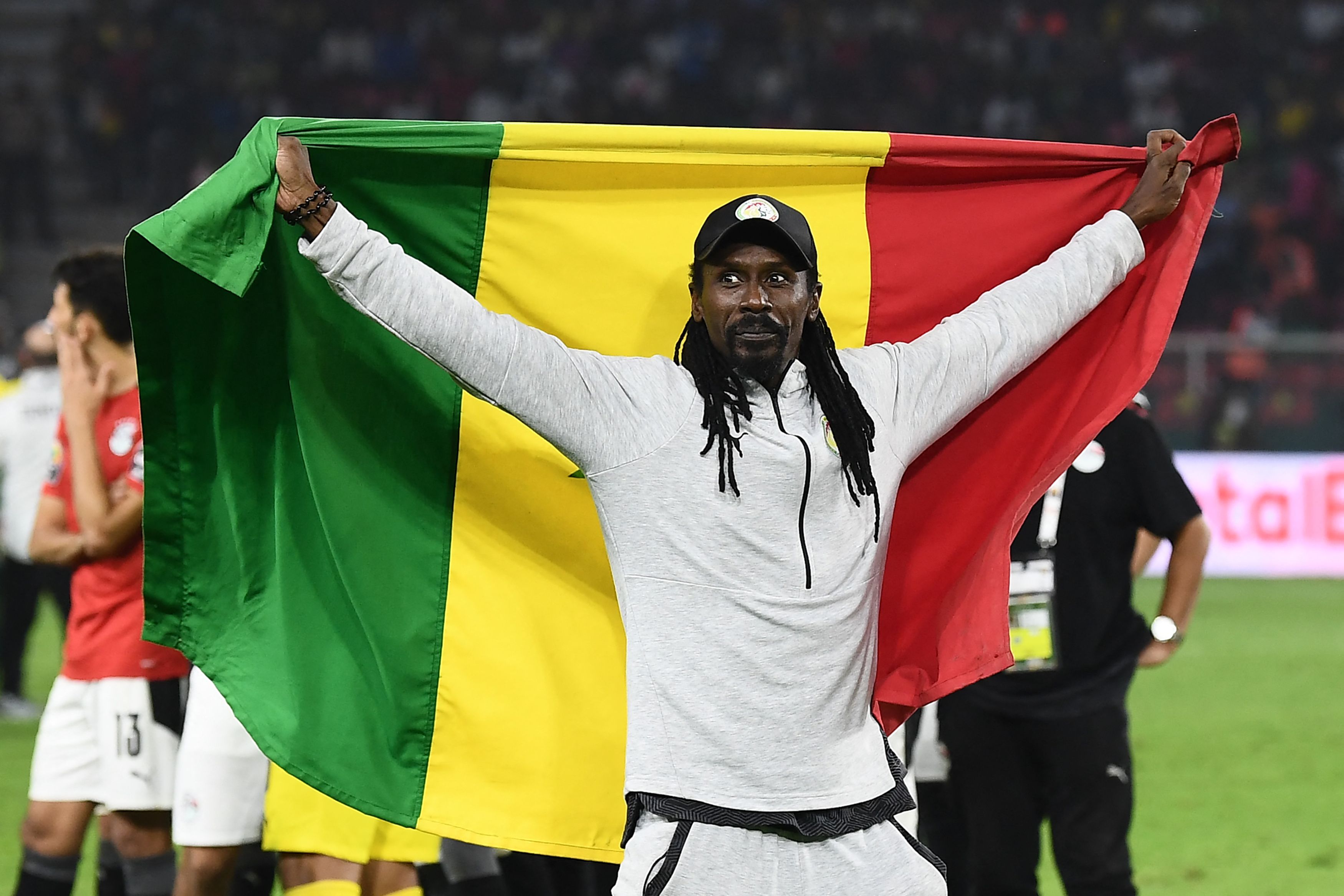 Aliou Cisse, pelatih timnas Senegal mengangkat bendera negaranya saat menjuarai Piala Afrika 2021.