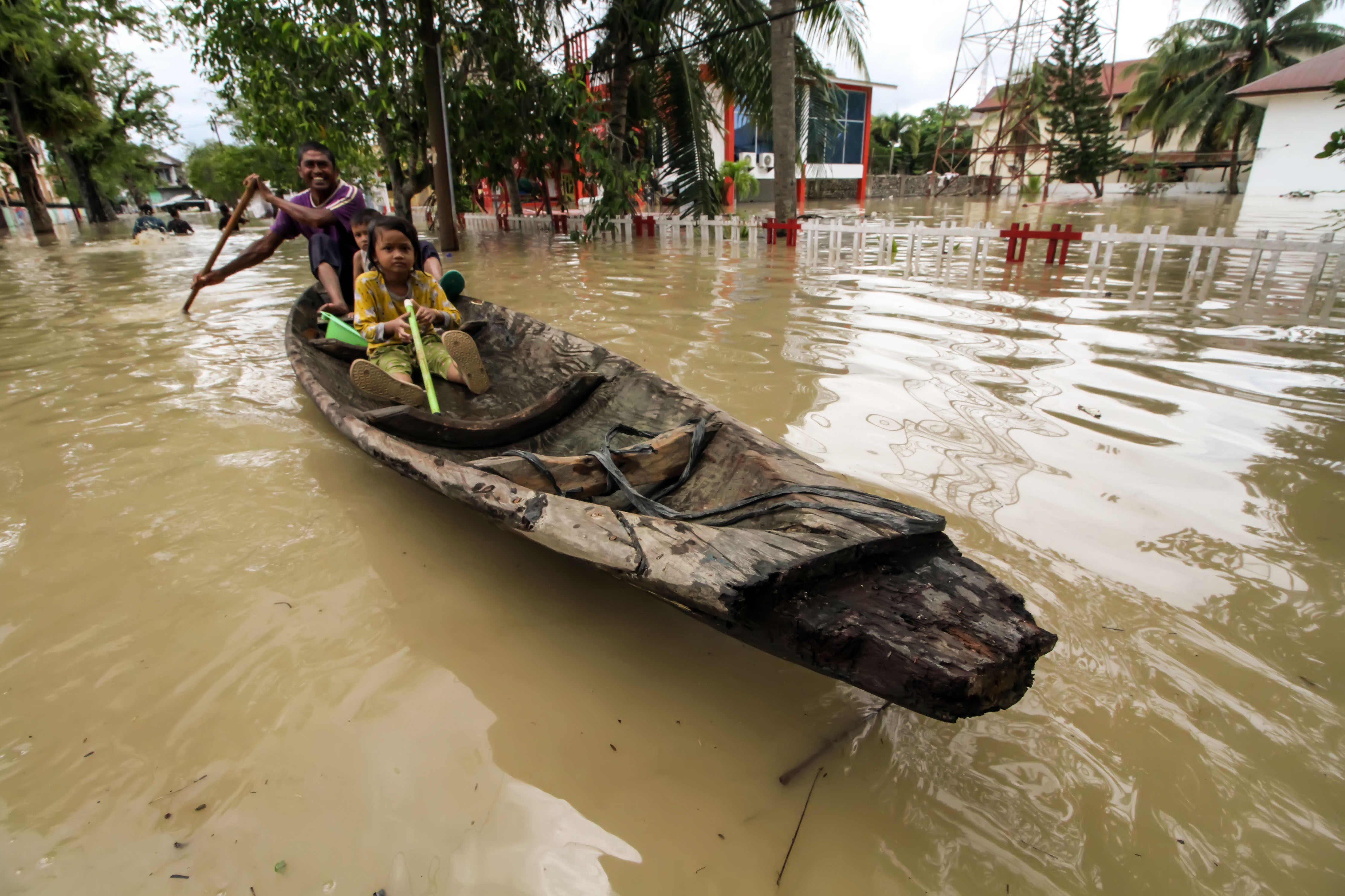 Warga bersama anaknya berusaha melintasi banjir dengan menggunakan perahu di Lhoksukon, Aceh Utara, Aceh Kamis (6/10).