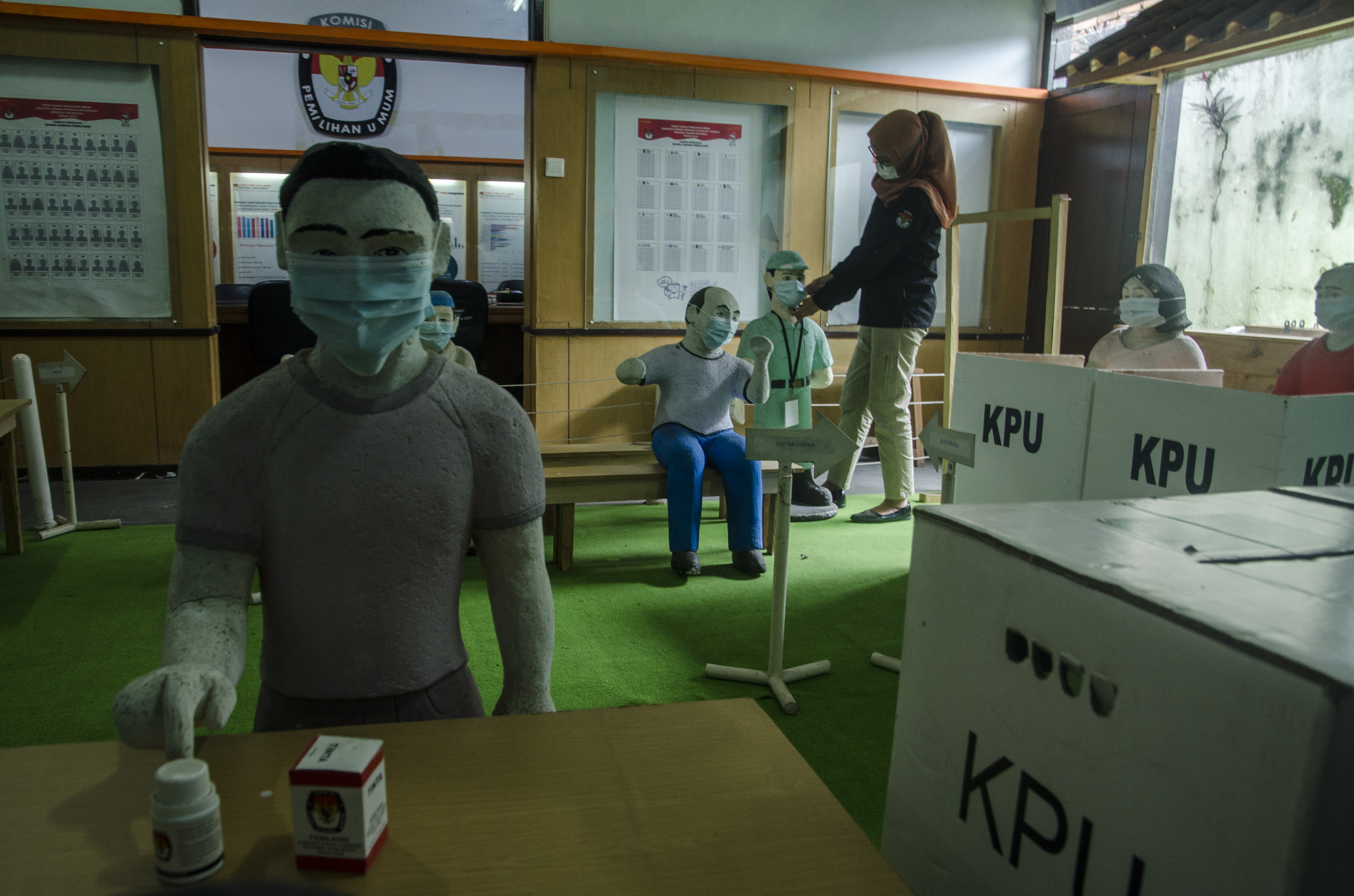 Petugas merapikan masker pada diorama suasana pemungutan suara di TPS saat Pemilu di Kantor KPU Jawa Barat, Bandung, Jawa Barat.