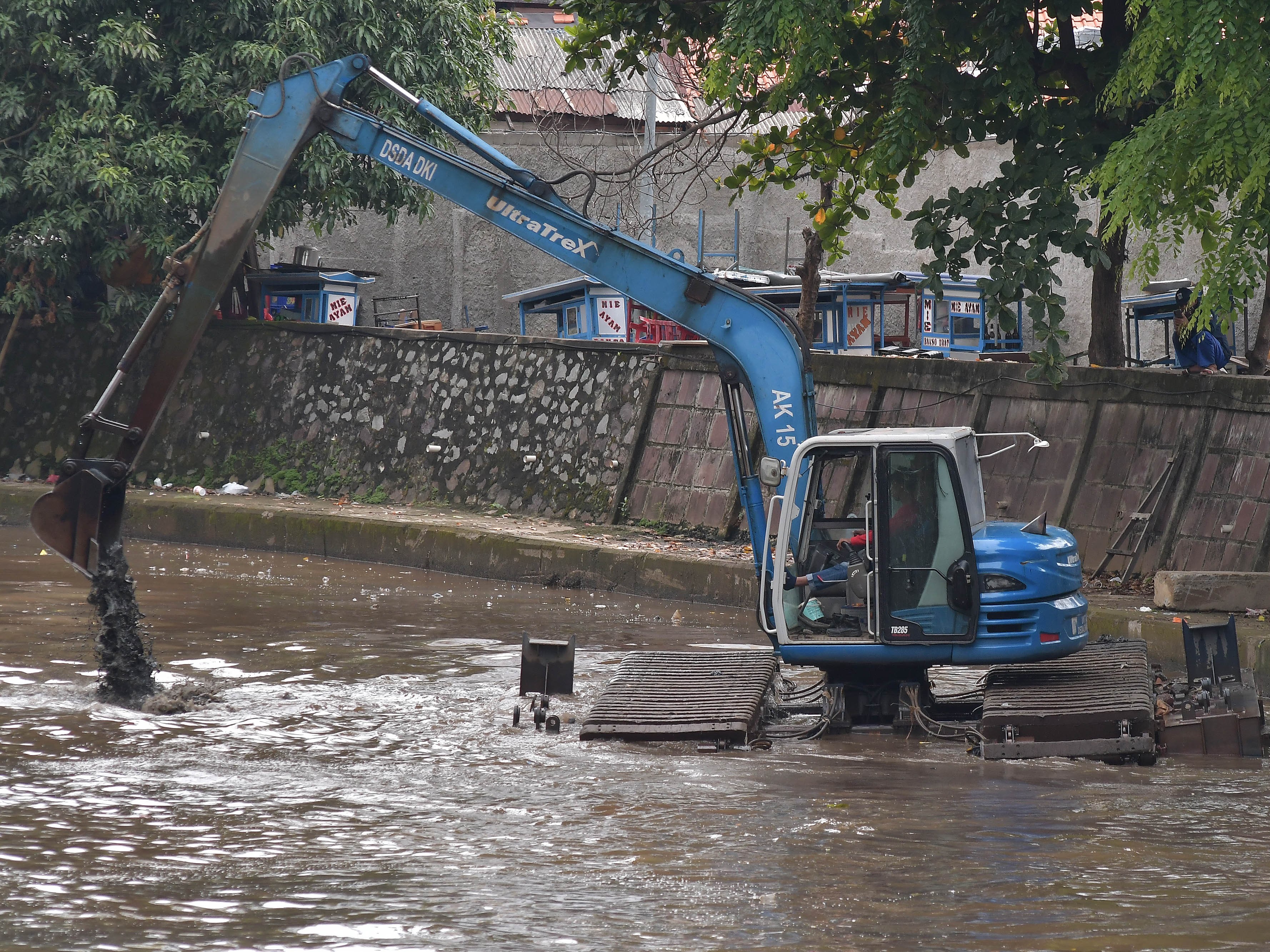 Petugas Sumber Daya Air (SDA) menggunakan alat berat mengeruk lumpur di aliran Kali Ciliwung, Gambir, Jakarta Pusat, Sabtu (8/10/2022).