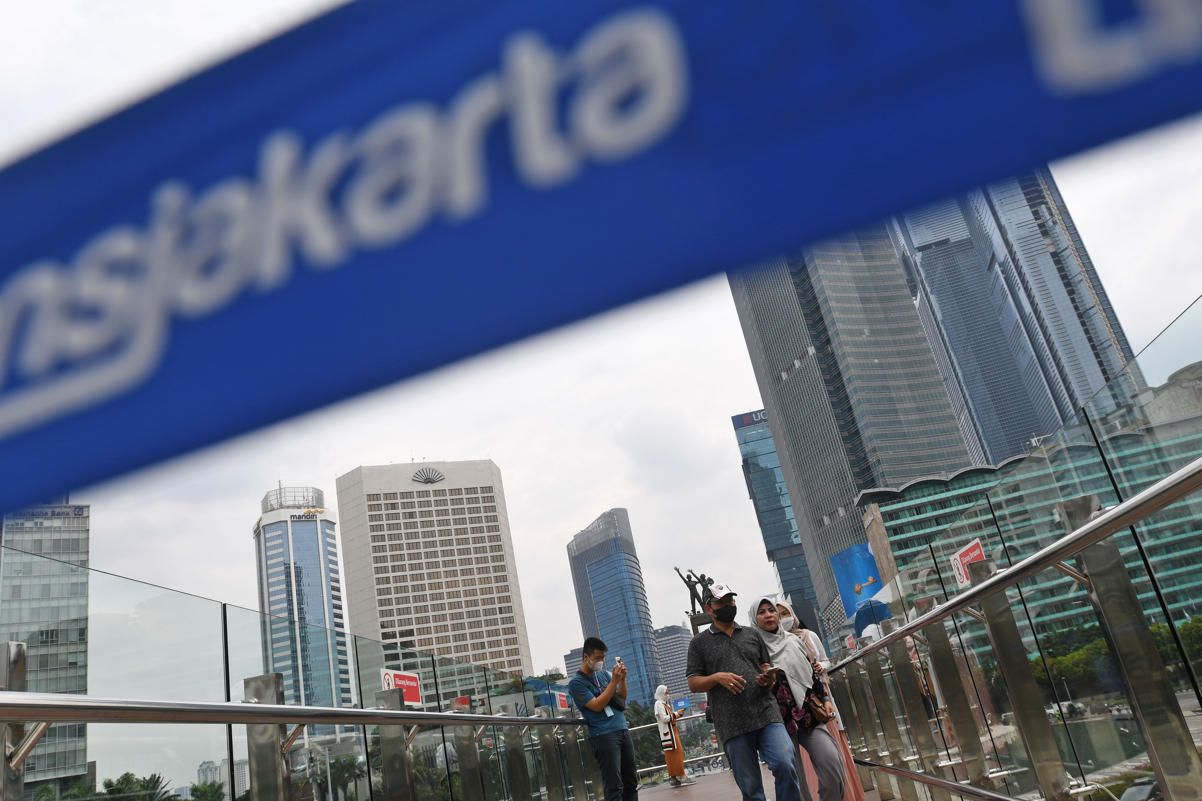 Potret warga berjalan di anjungan halte TransJakarta Bundaran HI.