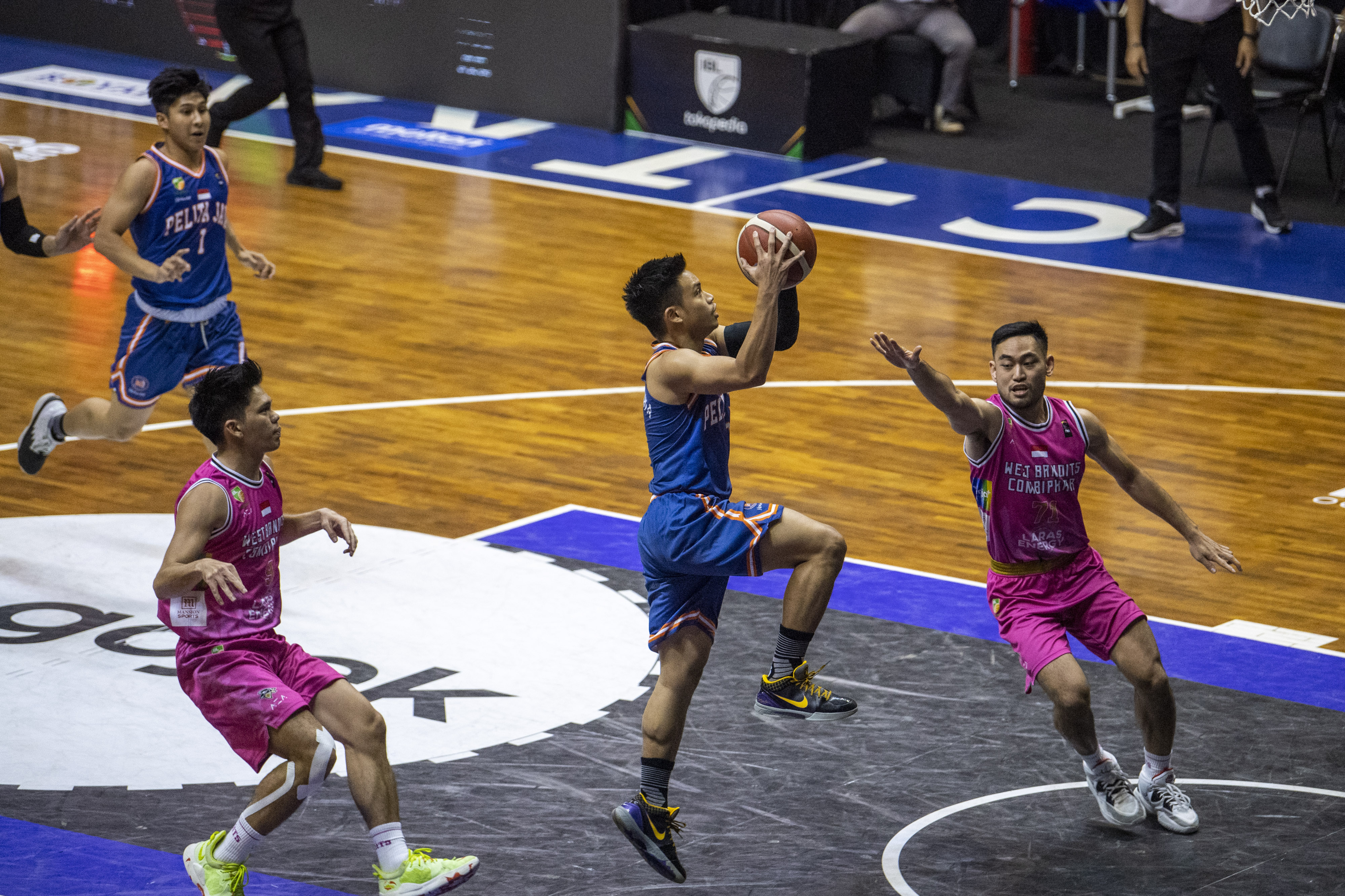 Pebasket Pelita Jaya melakukan lay up shoot dibayangi dua pebasket West Bandits.