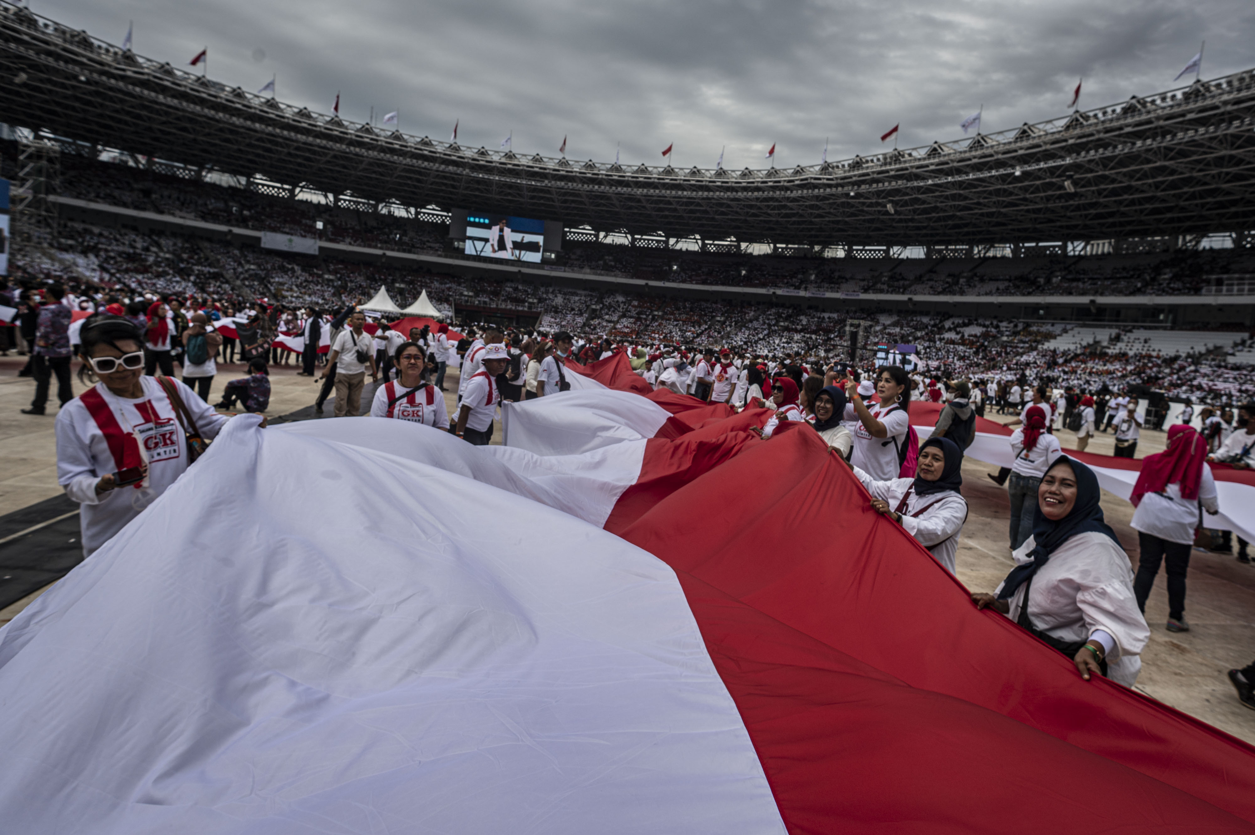 Sejumlah relawan membentangkan bendera Merah Putih di Stadion Utama Gelora Bung Karno, Jakarta, Sabtu (26/11).