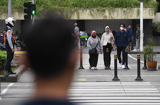 Warga menyeberang di Bilangan Thamrin, Jakarta sembari memakai masker