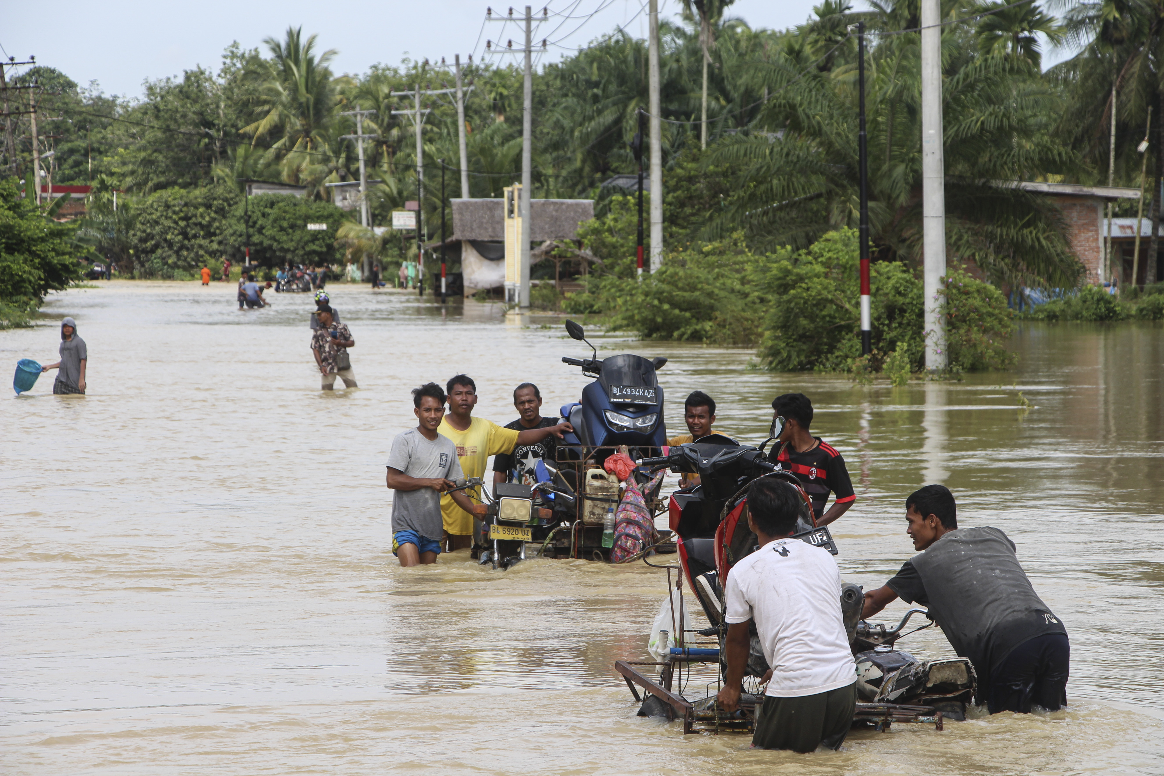 Sejumlah warga memberikan jasa angkut sepeda motor saat menembus jalan lintas Medan-Banda Aceh yang terendam banjir, Jumat (4/11).