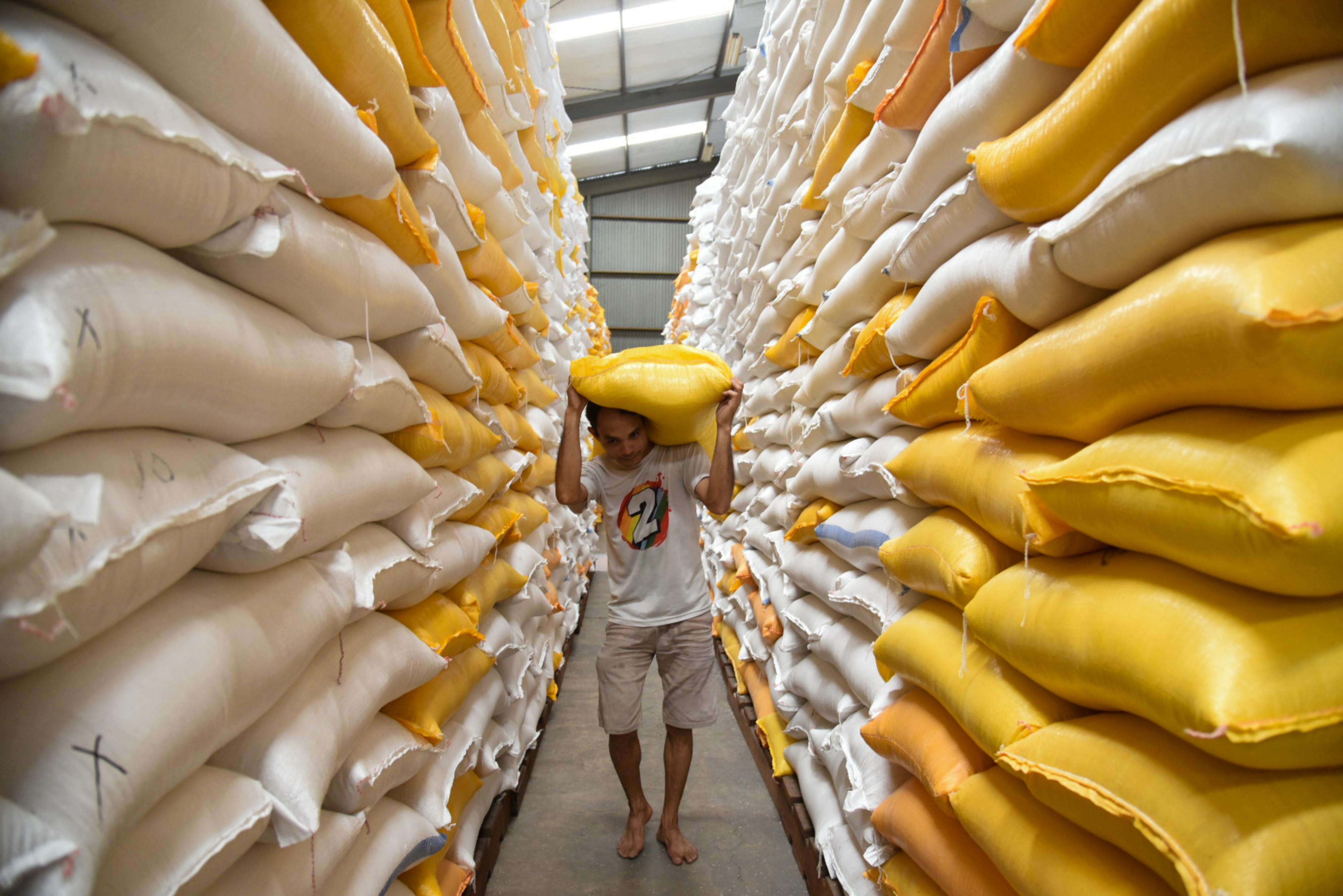 Pekerja mengangkut karung berisi beras di gudang Bulog.