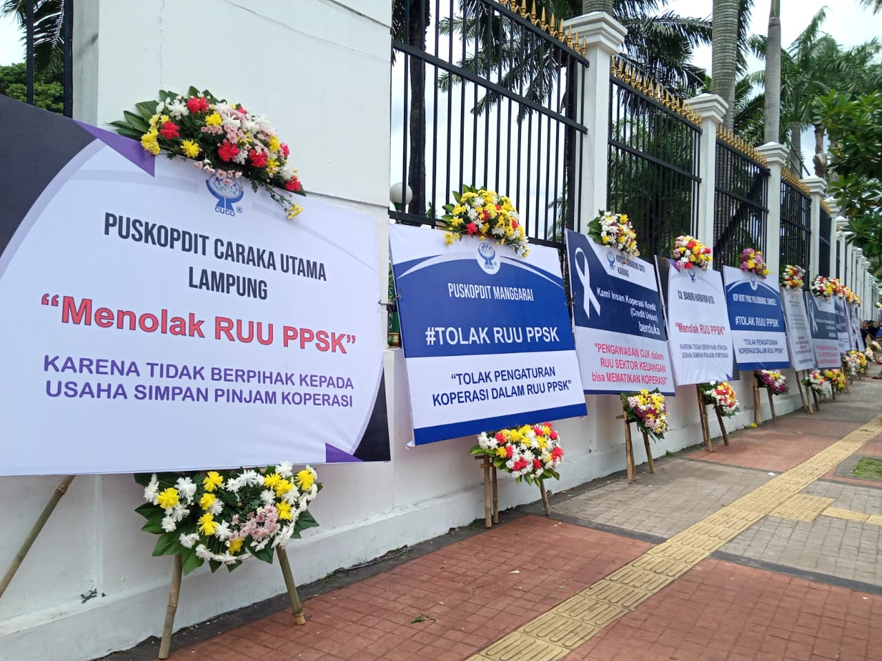 Papan bunga sebagai bentuk penolakan RUU PPSK menghiasi pagar tembok Gedung DPR dan MRR RI di Jakarta, Kamis (24/11).  