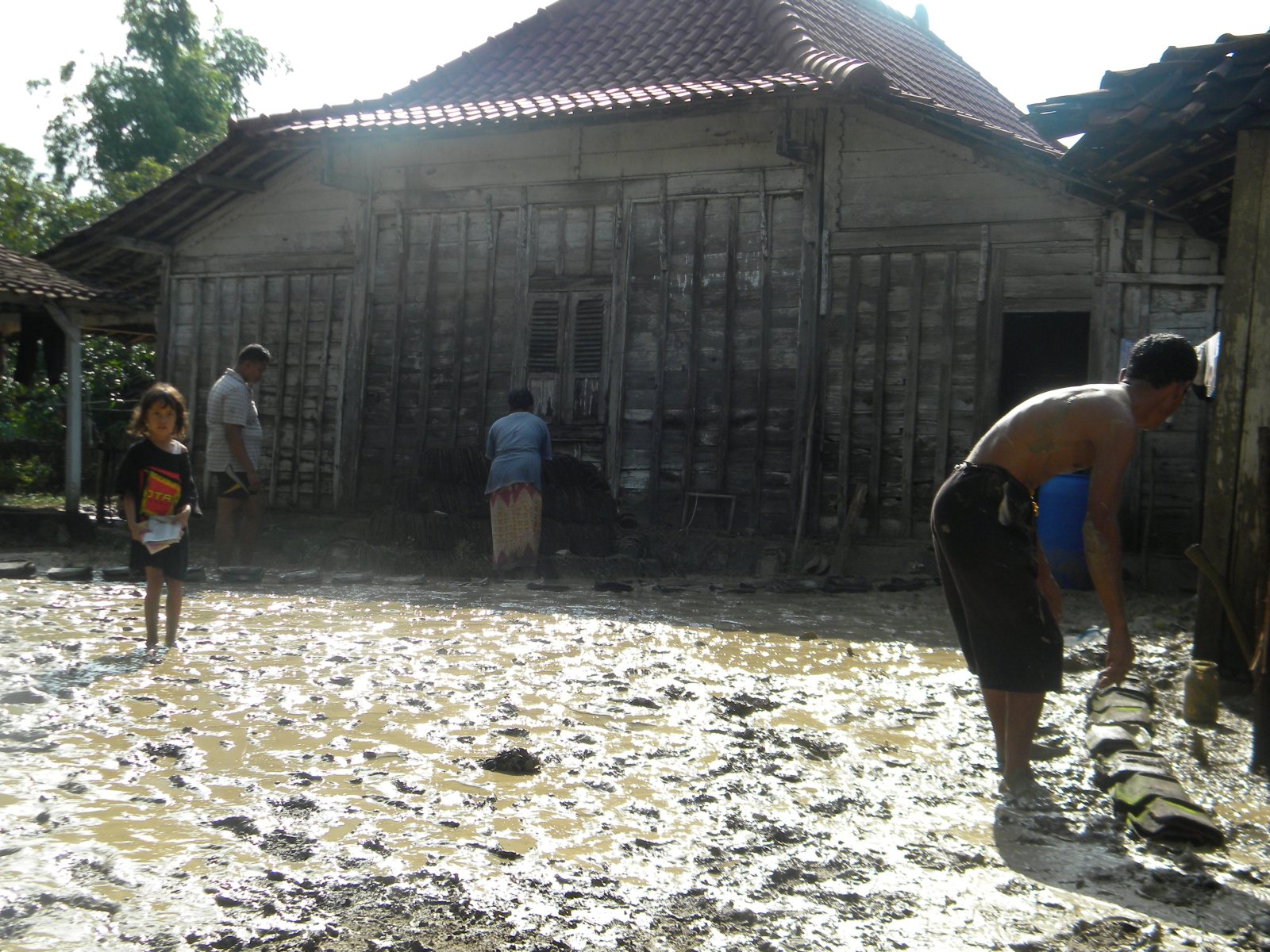 Warga membersihkan sampah-sampah yang ditinggalkan usai banjir bandang menerjang desanya.