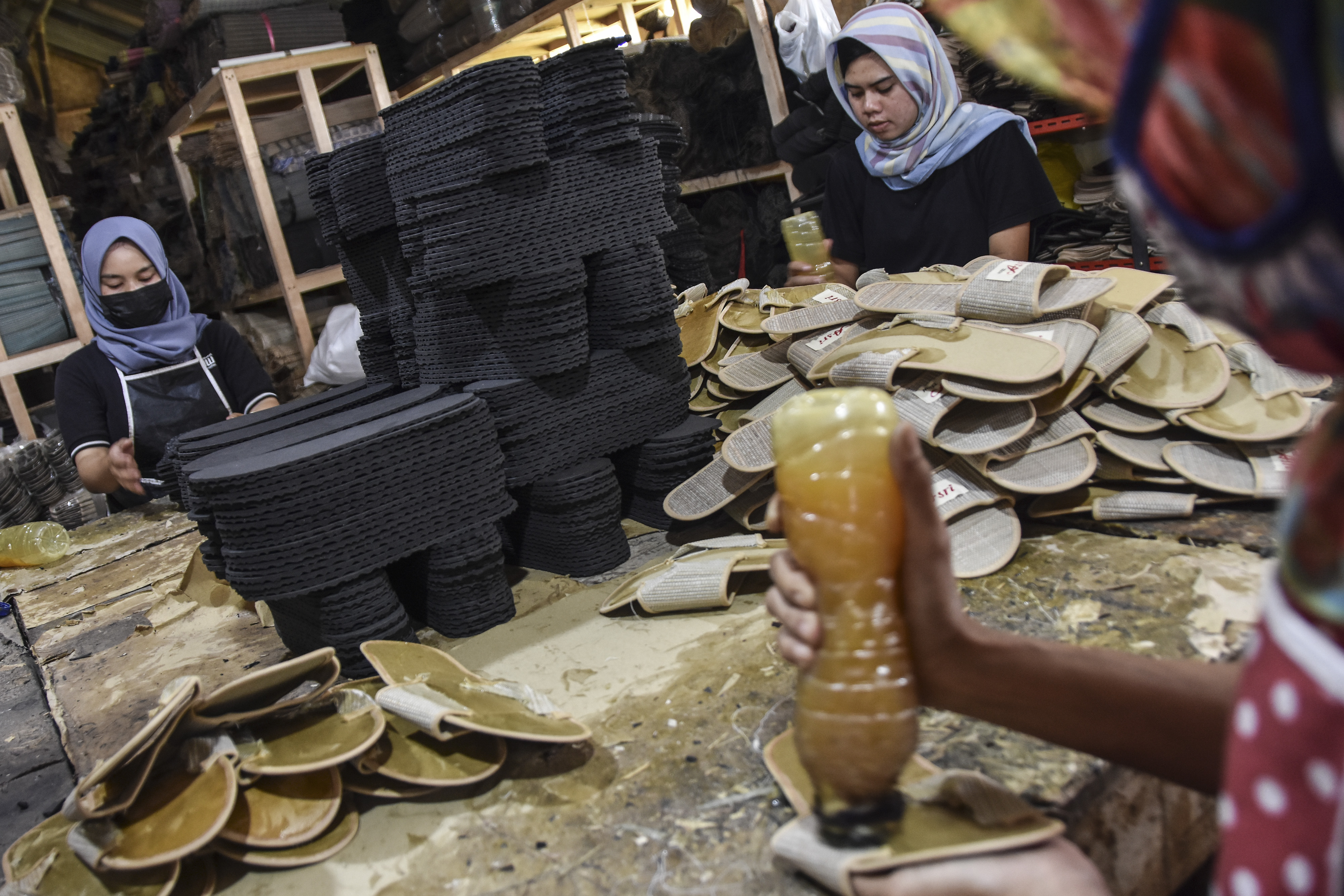 Pekerja menyelesaikan kerajinan sandal.